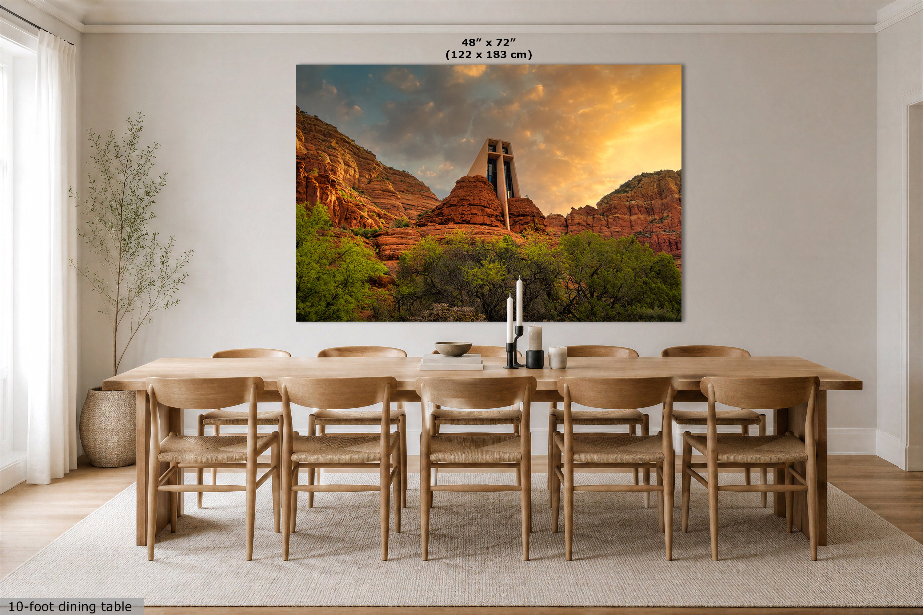 A large wall art print showing a desert canyon landscape at sunset hangs above a wooden dining table and chairs in a bright dining room. The print includes the text '48" x 72" (122 x 183 cm)' near the top.