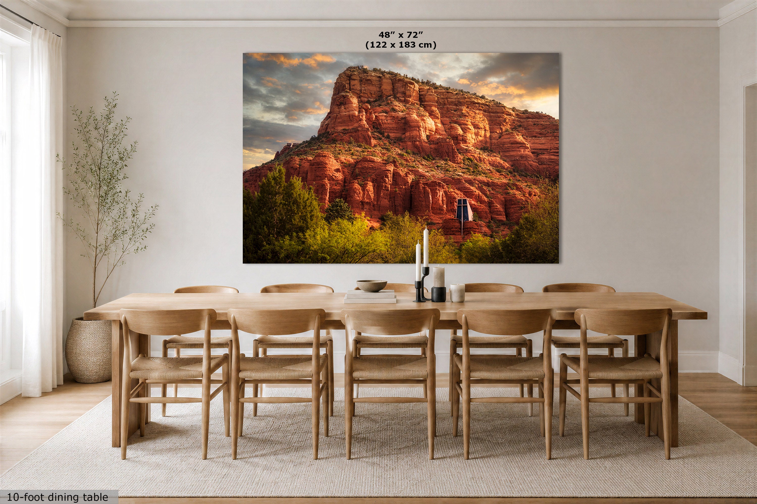 A large wall art print of a red rock desert canyon landscape is displayed above a wooden dining table and chairs in a bright, modern dining room. The print includes size text at the top reading 48" x 72" (122 x 183 cm).