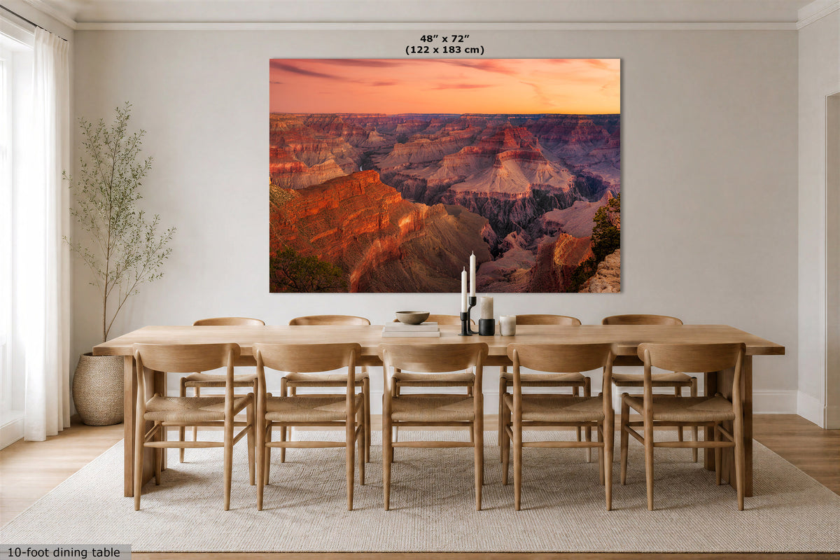 A large rectangular wall art print showing the Grand Canyon at sunset, displayed above a wooden dining table and chairs in a bright modern dining room. The print includes size text at the top reading 48" x 72" (122 x 183 cm).