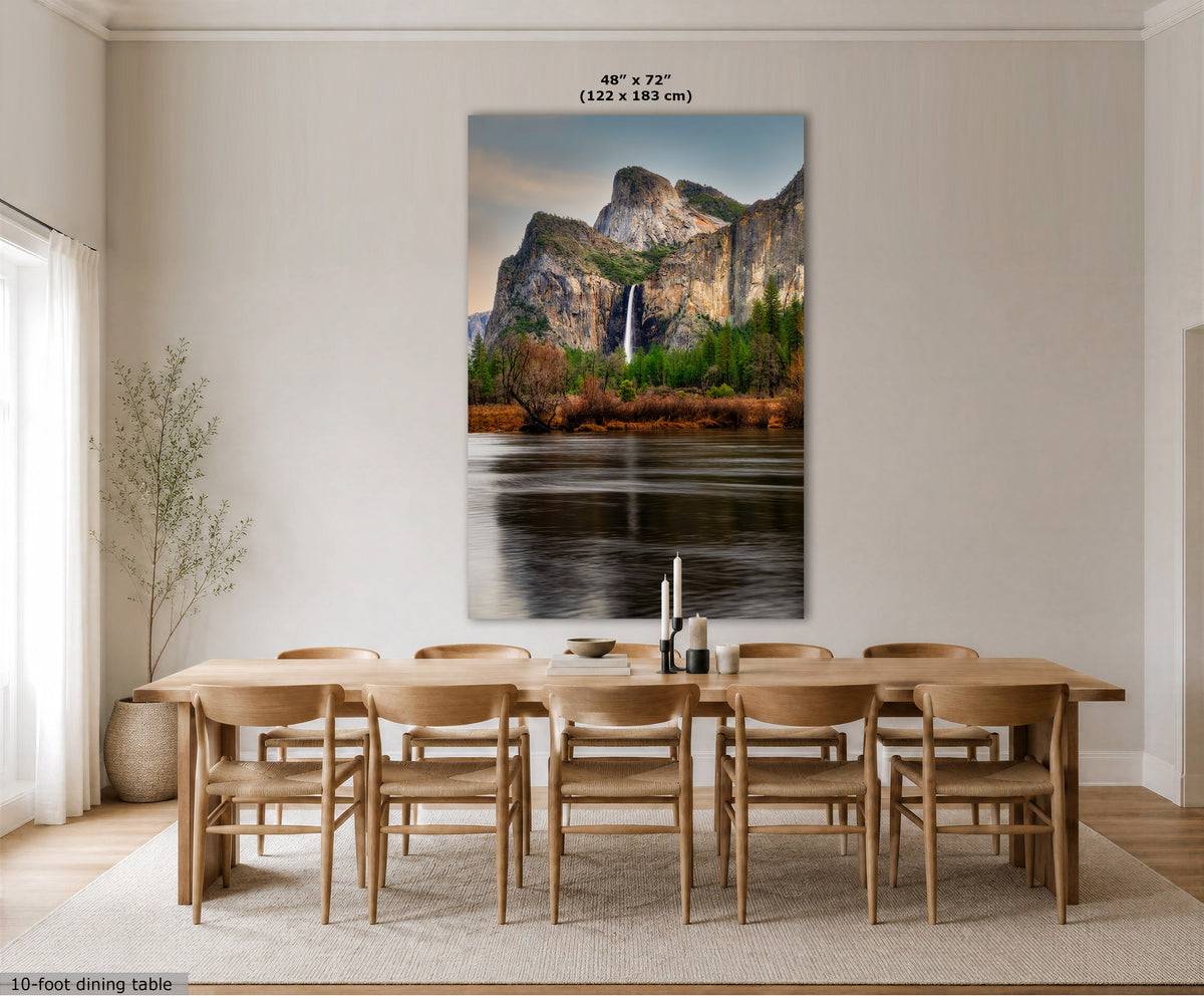 A large vertical wall art print showing a mountain landscape with a waterfall and reflective water, displayed above a wooden dining table and chairs in a bright dining room. Text at the top reads 48 x 72" (122 x 183 cm), and text at the bottom left says 10-foot dining table.