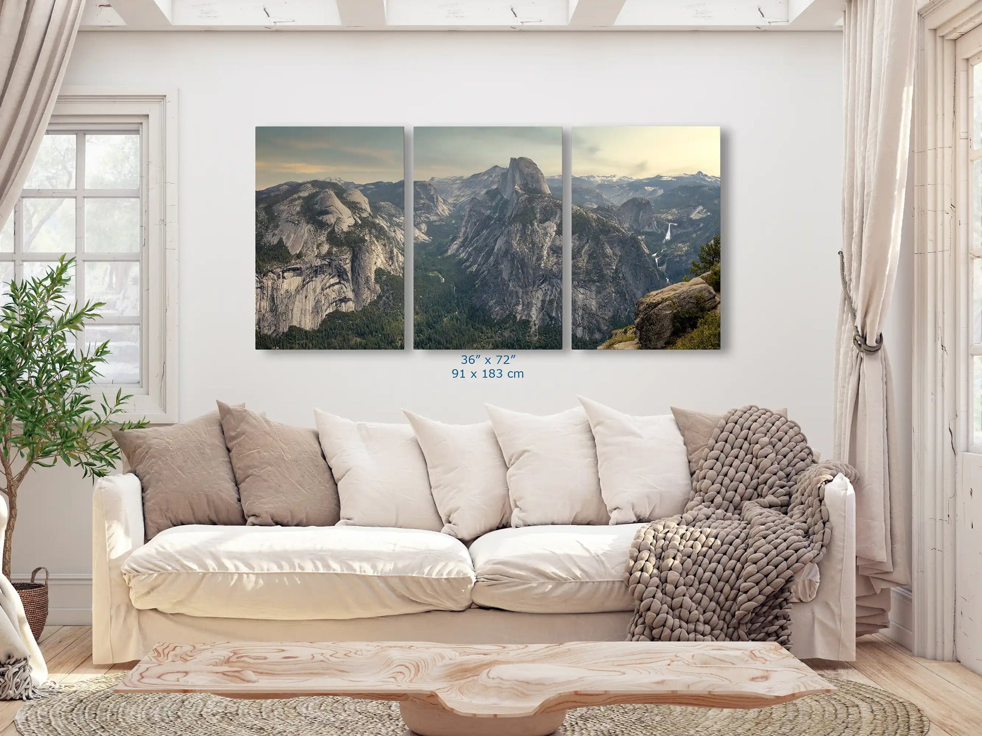 A 36x72-inch three-panel wall art of Glacier Point in Yosemite Valley displayed in a cozy living room with a white couch and beige cushions.