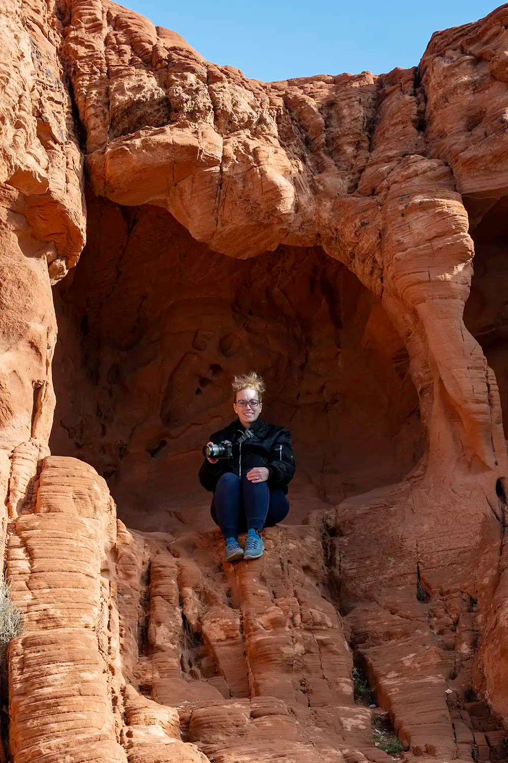 Jamie Lee Peterson sitting on red sandstone holding her camera