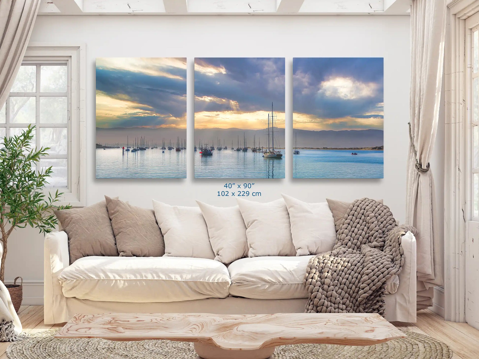 An impressive 40x90 inch canvas print spanning the wall above a living room couch, depicting a detailed sunrise scene at the harbor.
