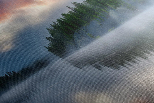 Close-up view of a canvas wall art showing a reflective Yellowstone Lake and forest with a stormy sunrise sky.