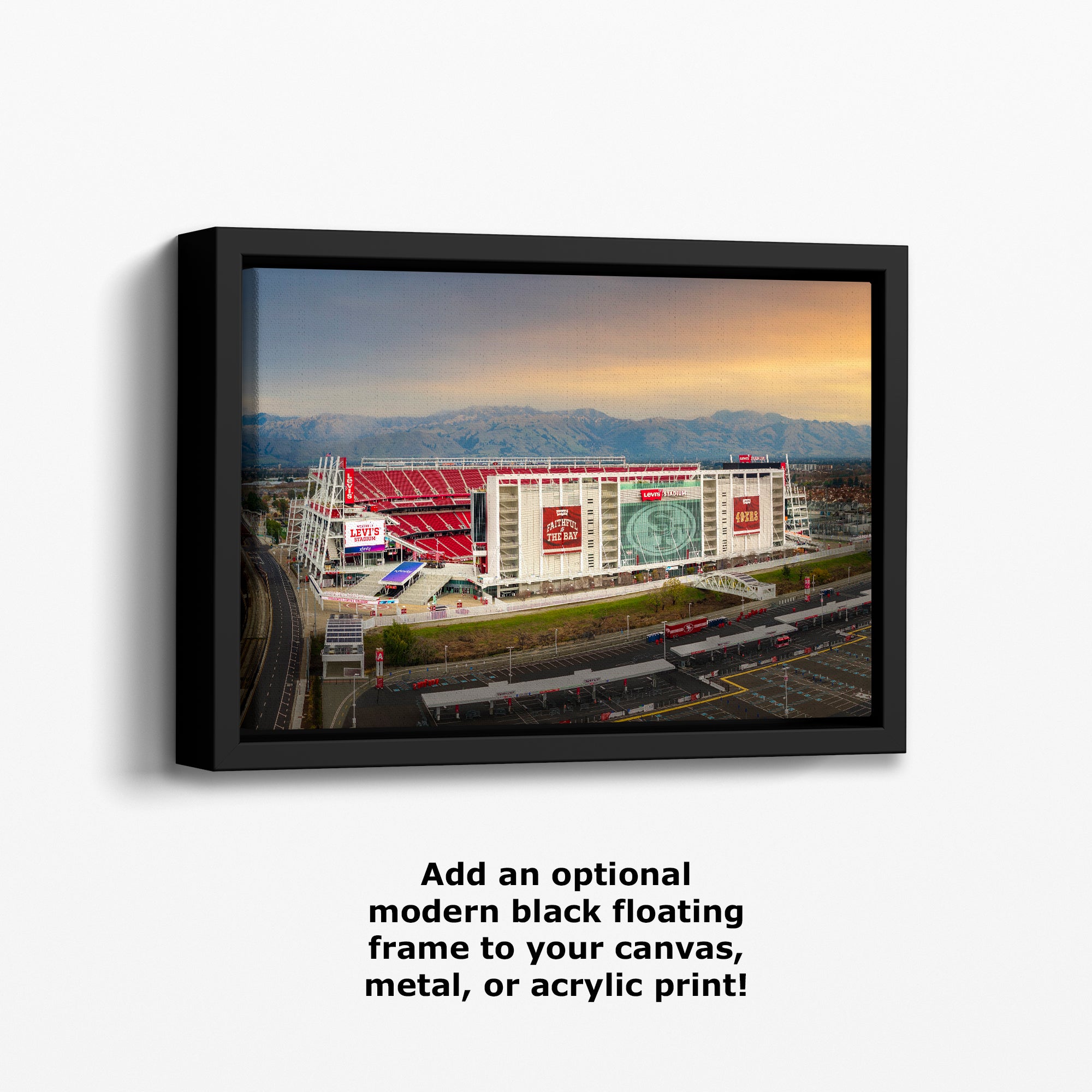a large stadium with a red roof and multiple advertisements on its exterior, set against a backdrop of mountains and a clear sky.