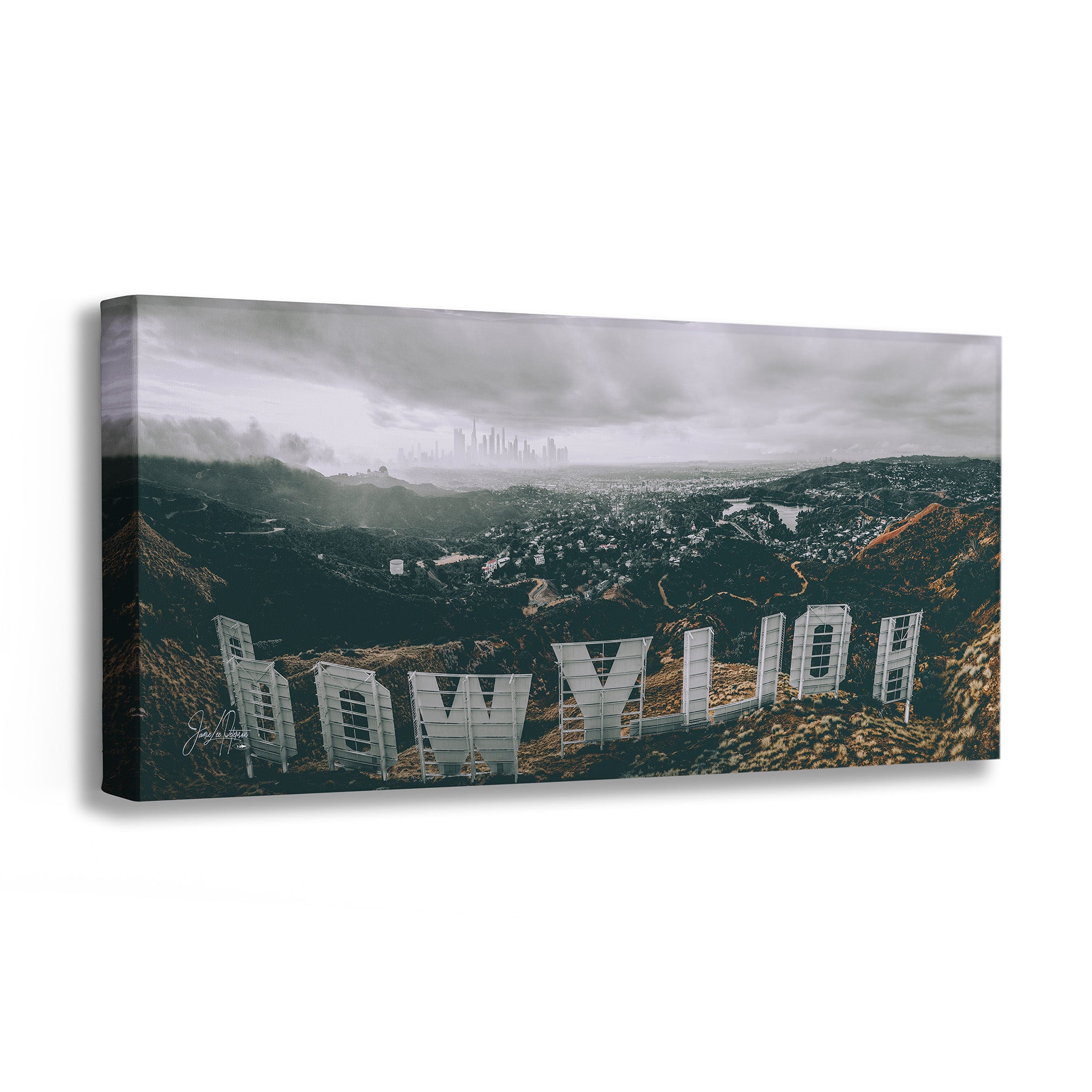 A rectangular canvas wall art print showing a dramatic aerial view of the Hollywood sign on a hillside with a hazy city skyline in the distance, photographed against a plain white background.