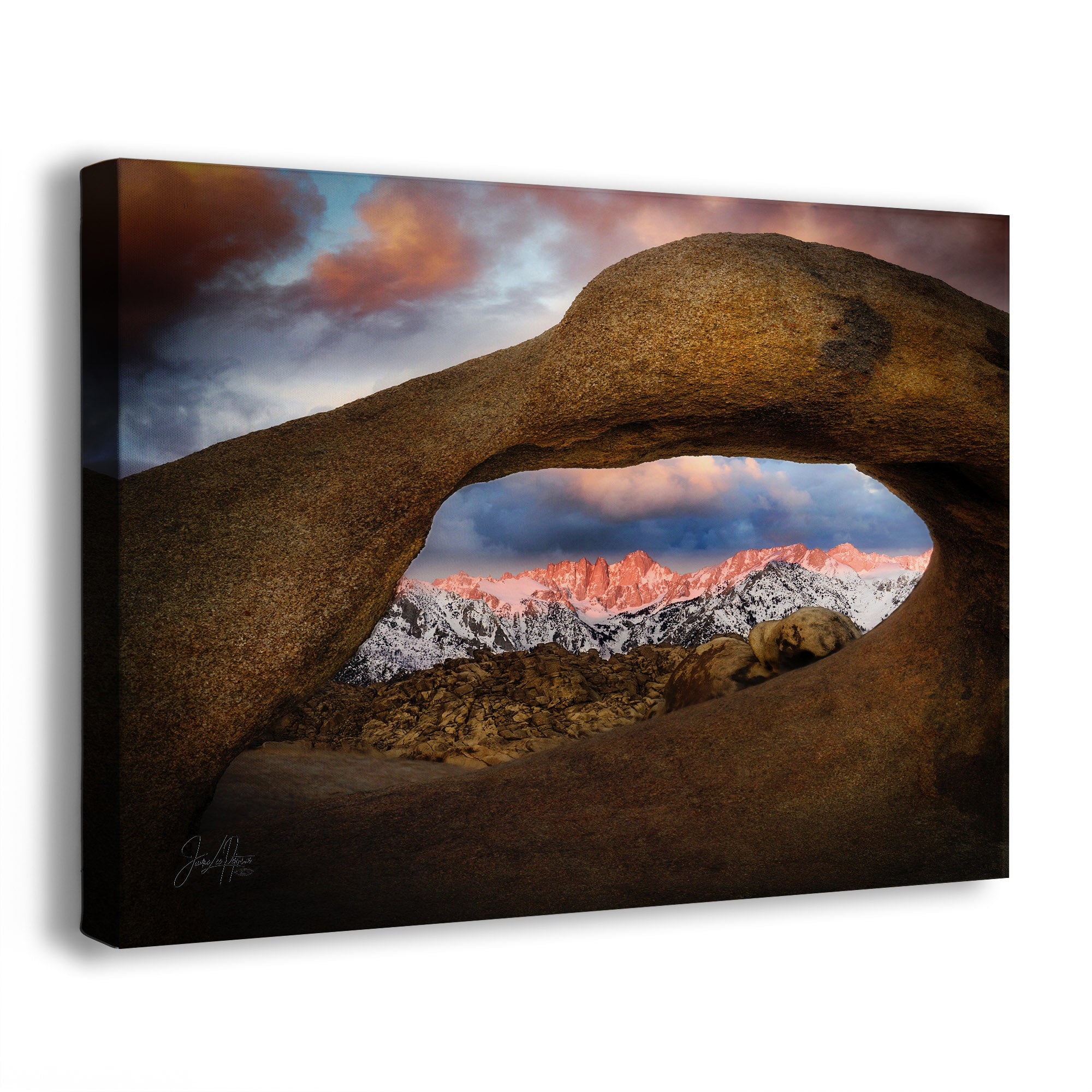 Rocks forming an arch with a mountain range and colorful sky in the background