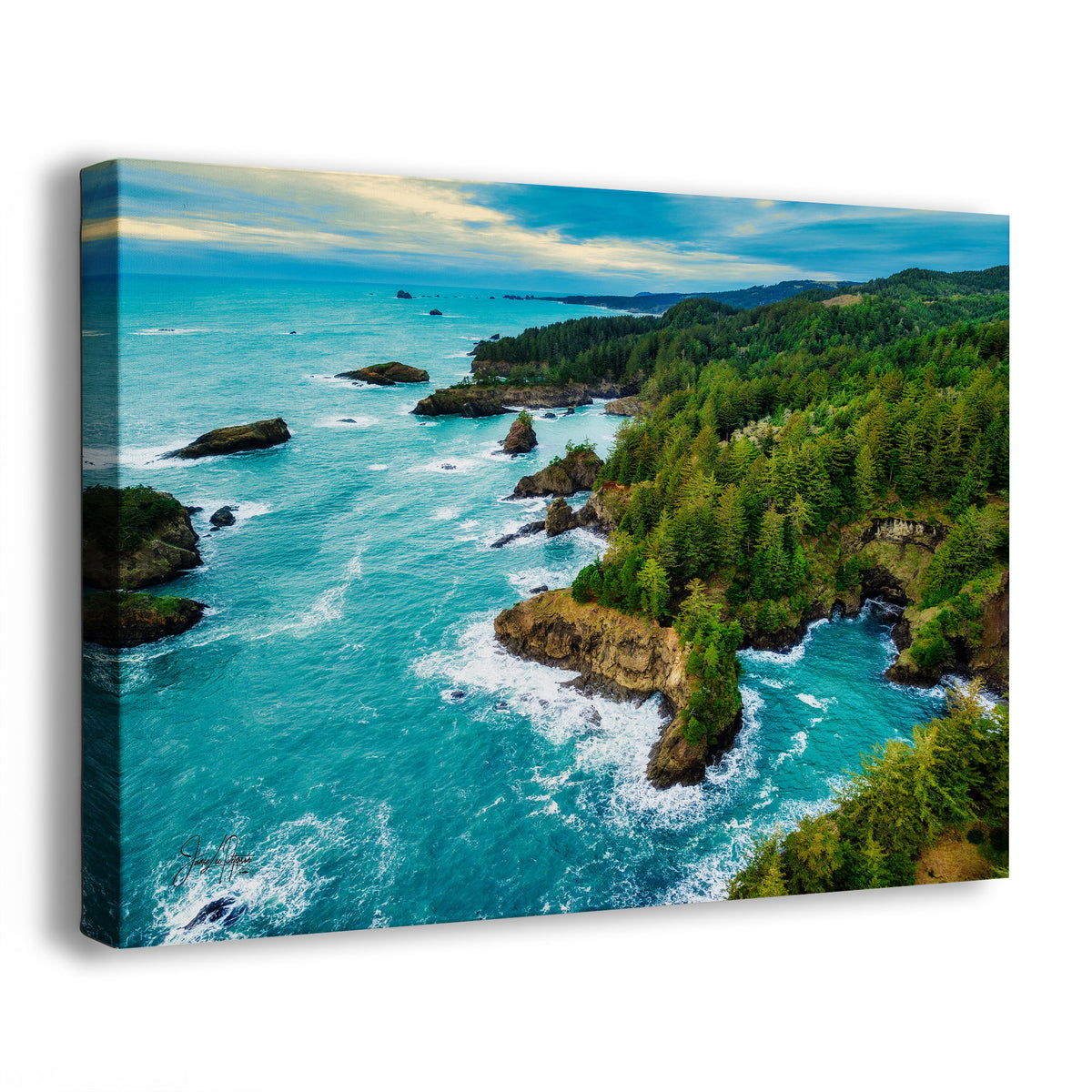 A canvas wall art print showing an aerial coastal landscape with bright turquoise ocean water, rocky shoreline, dense green forest, and a blue sky with soft clouds, photographed on a clean white background.