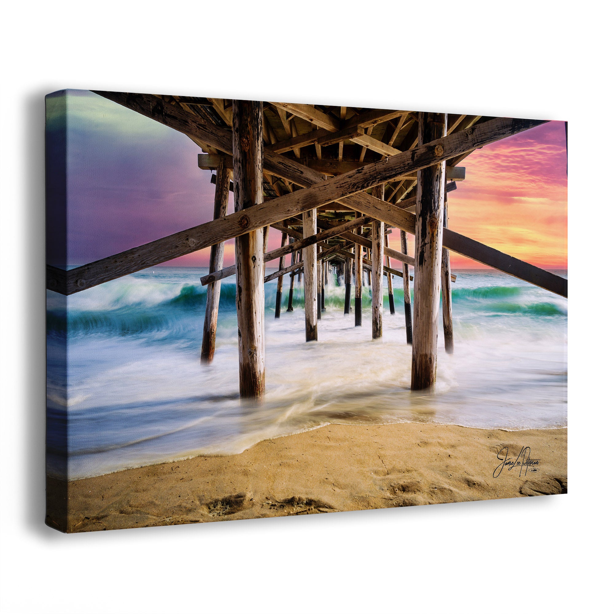 Canvas print of a beach scene under Balboa Pier in Newport Beach, California show ocean waves slowed down under a colorful sunset sky. 