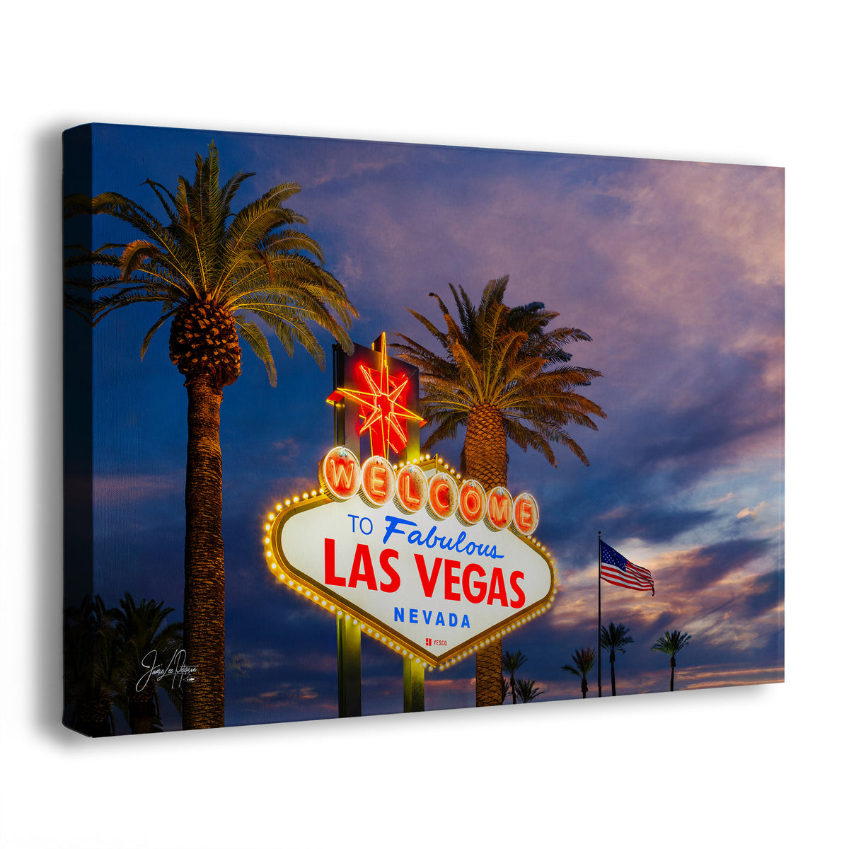 A rectangular wall art print showing the illuminated 'Welcome to Fabulous Las Vegas Nevada' sign between two palm trees against a dramatic purple and blue sunset sky. The print is photographed at a slight angle on a clean white background.
