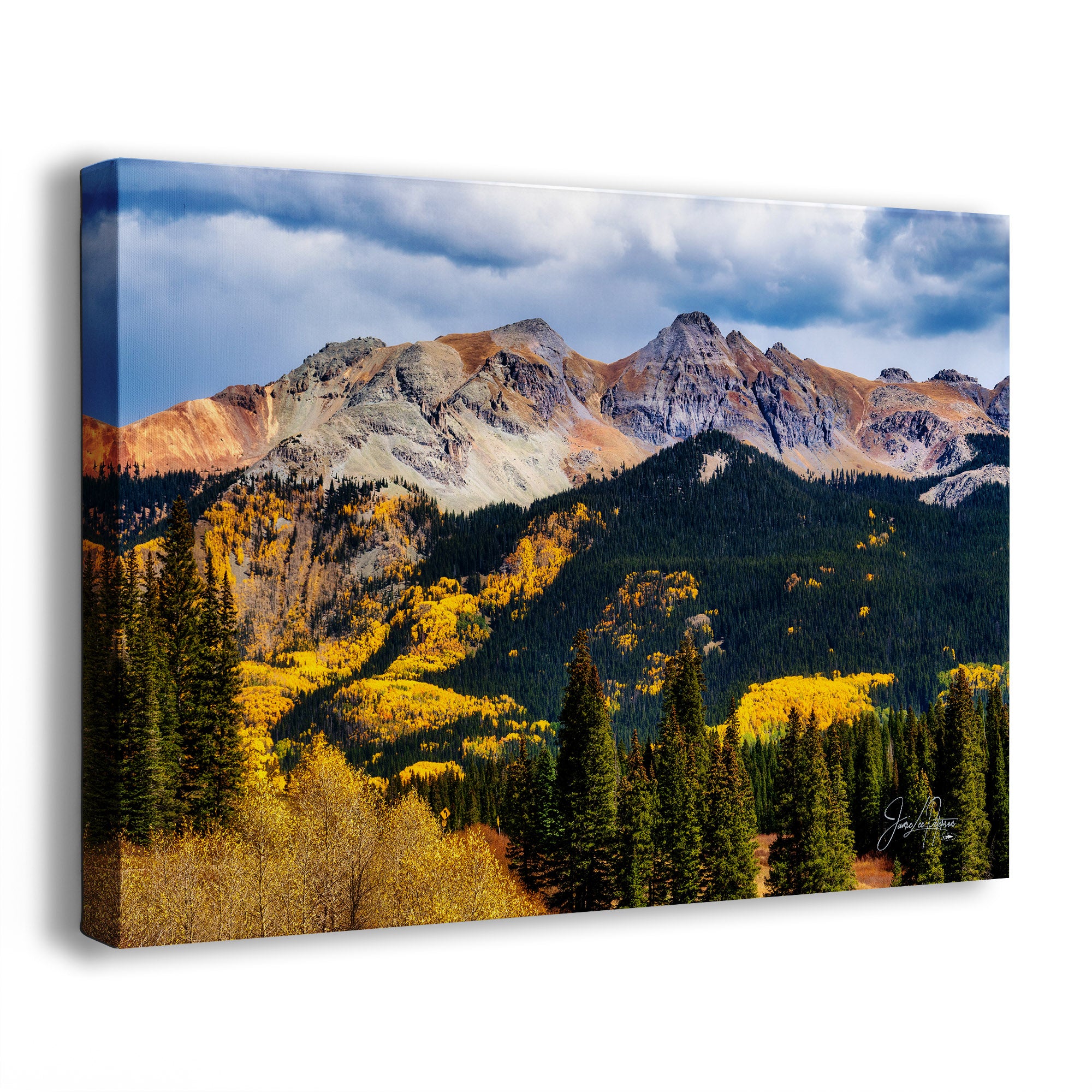 A canvas wall art print showing a Colorado mountain landscape with rocky peaks, blue-gray clouds, yellow aspen tree autumn foliage, and dark evergreen trees, photographed against a plain white background.