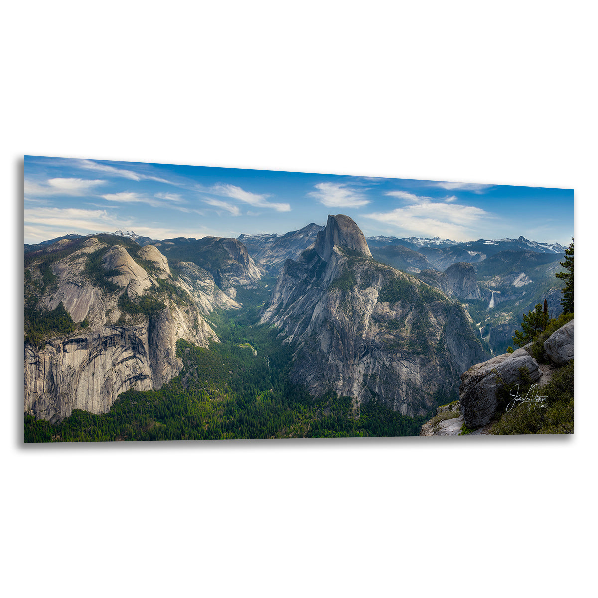 A panoramic landscape art print depicting Half Dome and the valley of Yosemite National Park under a blue sky with light clouds, shown as a physical canvas print with a subtle drop shadow on a white background.