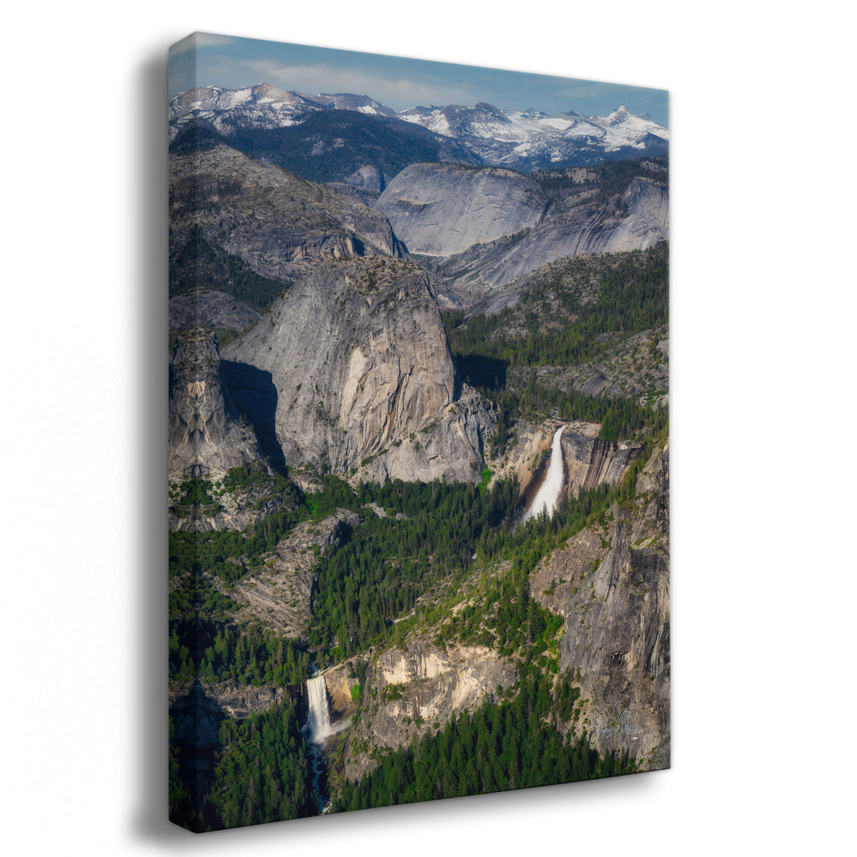 A vertical canvas wall art print depicting a dramatic mountain landscape from Yosemite National Park of Nevada Falls and Vernal Falls with granite cliffs, evergreen forests, and a waterfall, shown at a slight angle against a white background.