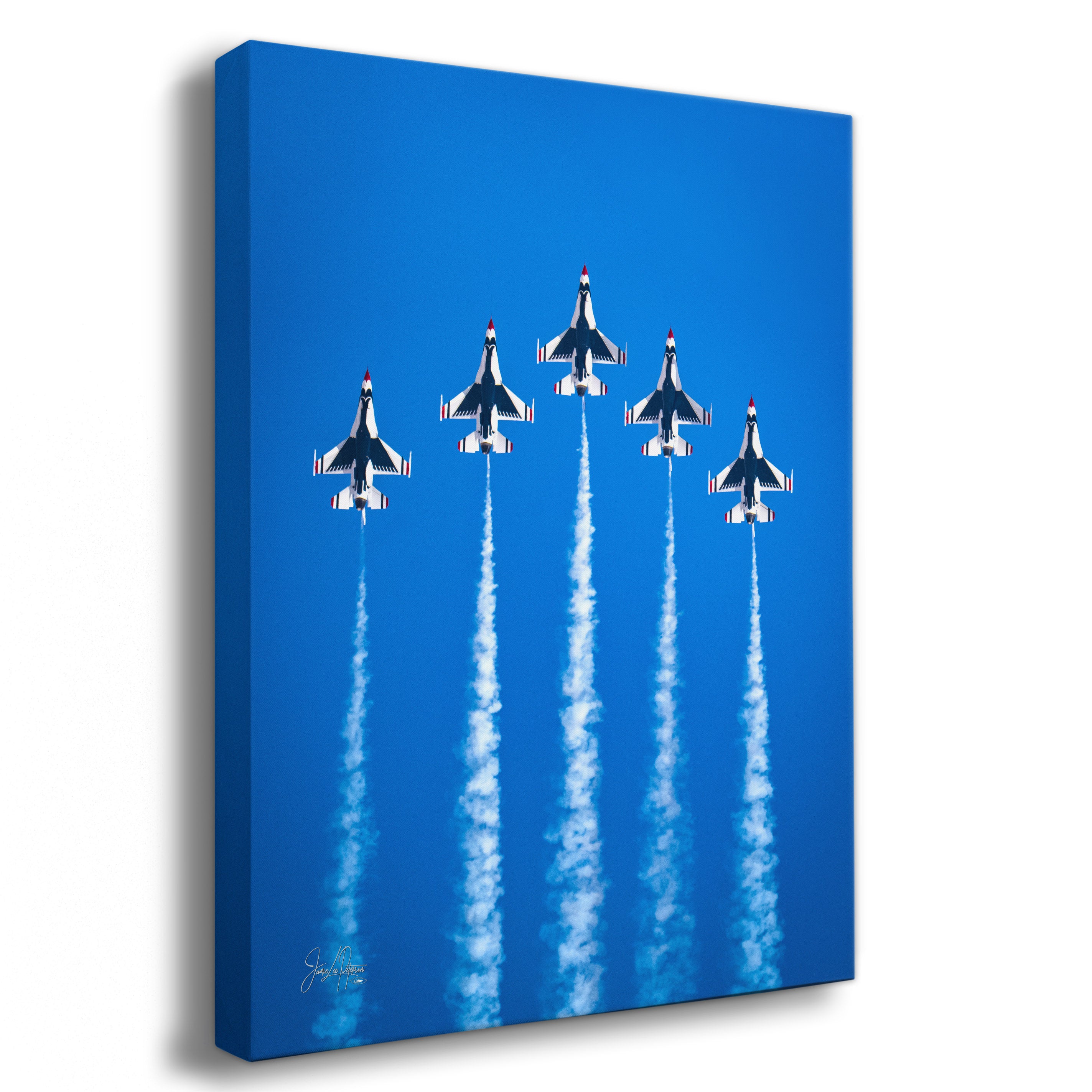 A vertical canvas wall art print showing five USAF Thunderbird fighter jets flying in formation and leaving white smoke trails against a bright blue sky, photographed on a white background.