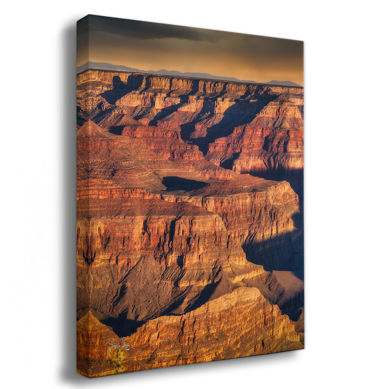 A vertical canvas wall art print depicting the Grand Canyon under a dramatic golden sky, shown at a three-quarter angle against a plain white background.