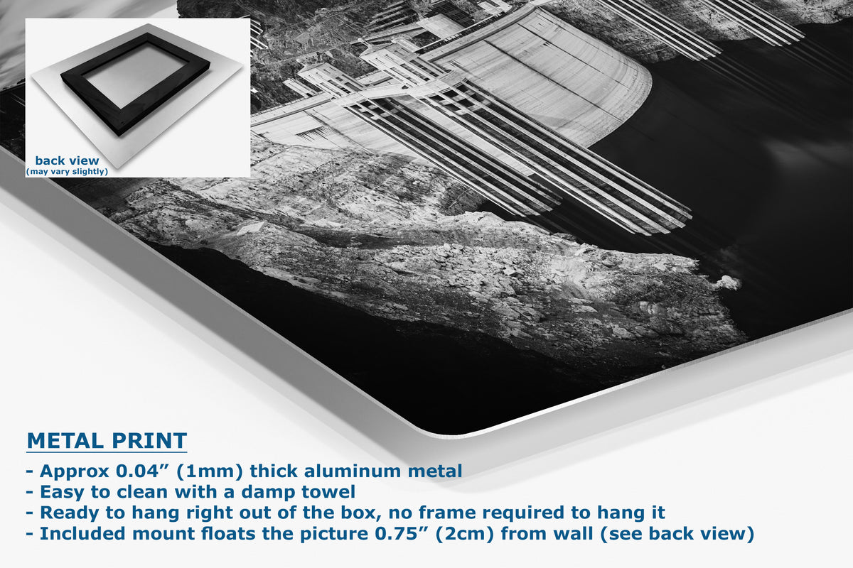 A large black and white wall art print showing a dam and rocky landscape, displayed at an angle with a small inset showing the back view. Text on the image describes the product as a metal print with aluminum frame details and hanging instructions.
