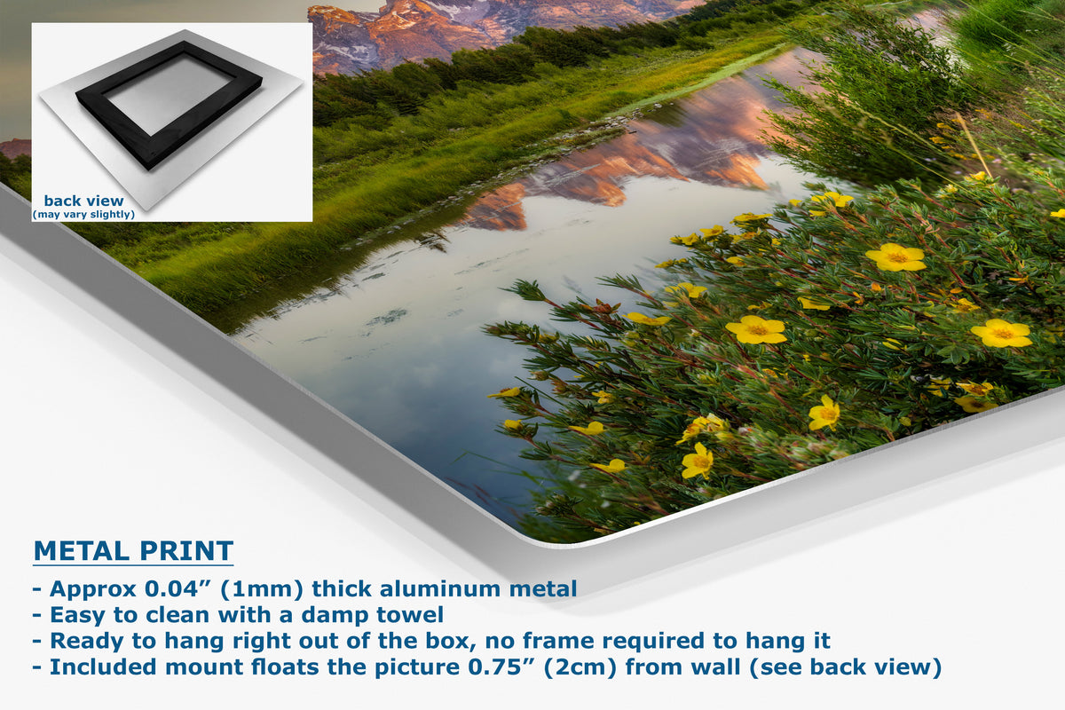 Metal wall art print showing a scenic landscape with a reflective pond, green hills, mountains, and yellow flowers, displayed at an angle with product features and text overlays on a white background.