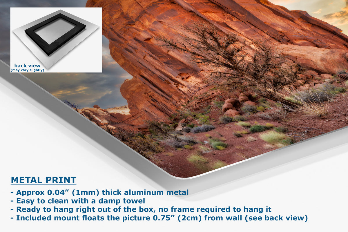 A metal wall art print showing a desert rock landscape, presented at an angle with product details and text on a white background. An inset shows the back view of the frame, and the text highlights aluminum metal construction and mounting features.