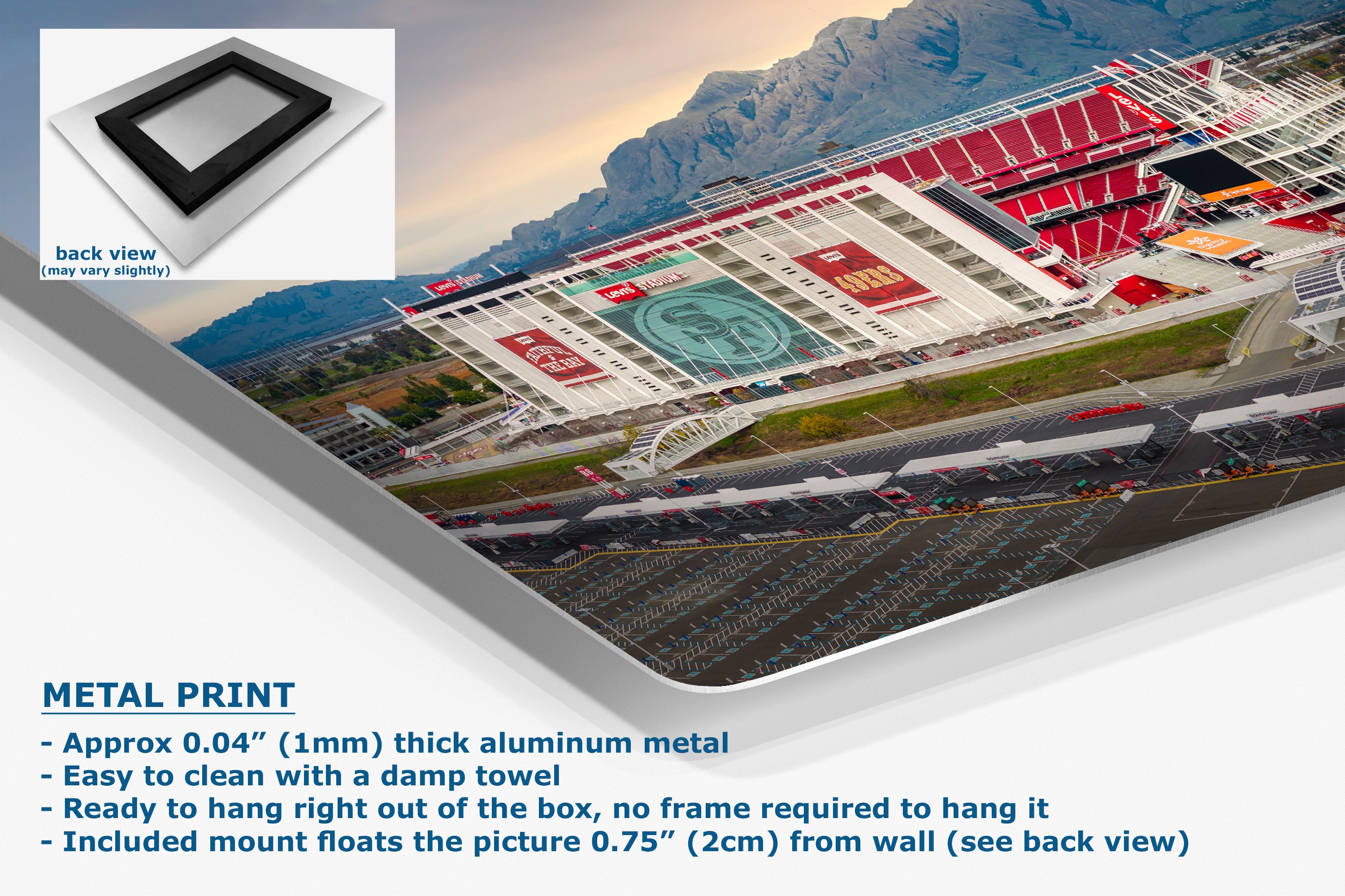 A corner view of an aluminum metal wall art print showing a mountain city stadium scene, presented at an angle with a small back-view inset and product text on a white background.