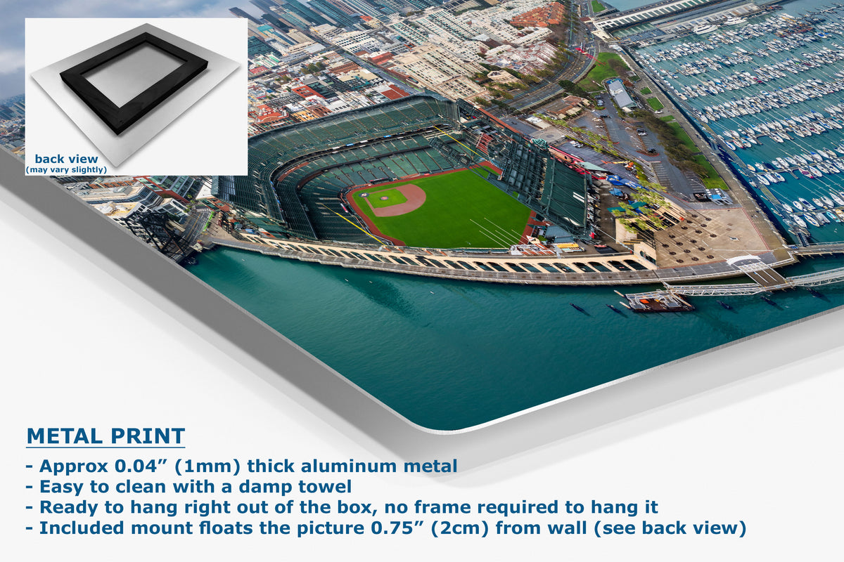 A corner view of an aluminum metal wall art print showing an aerial view of a baseball stadium by the water, with product details and a small back-view inset on a white background.