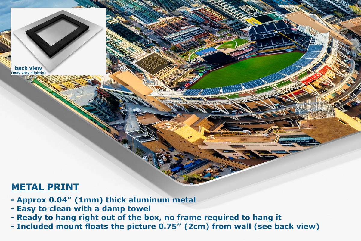 A corner view of an aluminum metal wall art print showing an aerial view of a stadium and surrounding urban area, displayed at an angle, with product details and text on a white background. Includes a small inset showing the back view of the frame/mount.