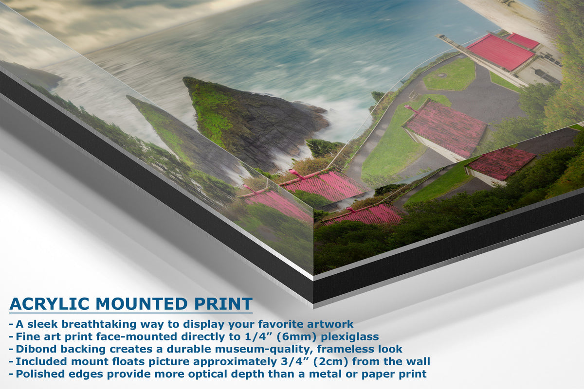 An acrylic-mounted art print shown at an angle, featuring a coastal landscape with blue water, green land, and buildings with red roofs. Text on the left describes the acrylic mounted print features.