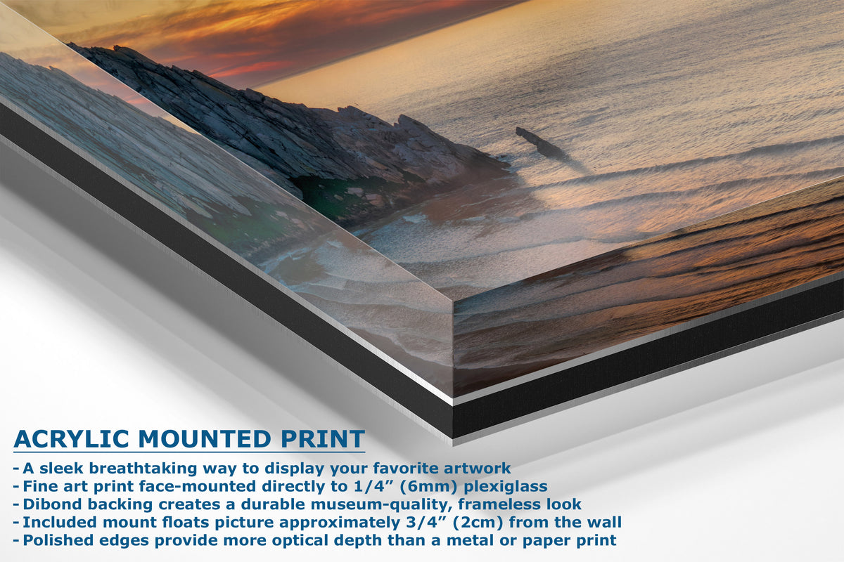 Acrylic mounted art print of a coastal sunset scene, shown at an angle with descriptive text highlighting its frameless plexiglass finish and mounting details.