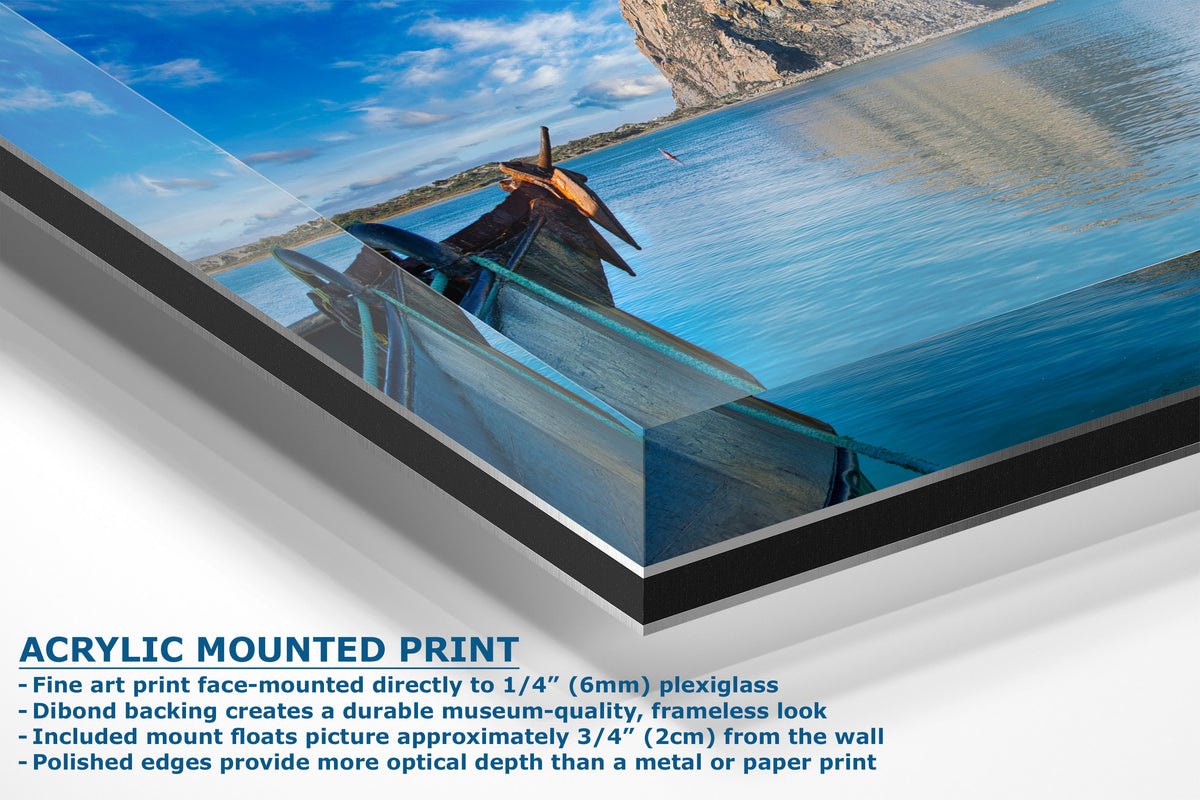 Acrylic mounted art print showing a scenic photograph of a wooden boat on blue water with cliffs in the background, presented at an angle with descriptive text below.