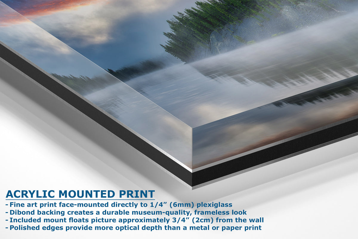 A corner view of an acrylic mounted print of a landscape photograph showing a misty forest under a cloudy sky, with descriptive text detailing the frameless mounting process on a white background.