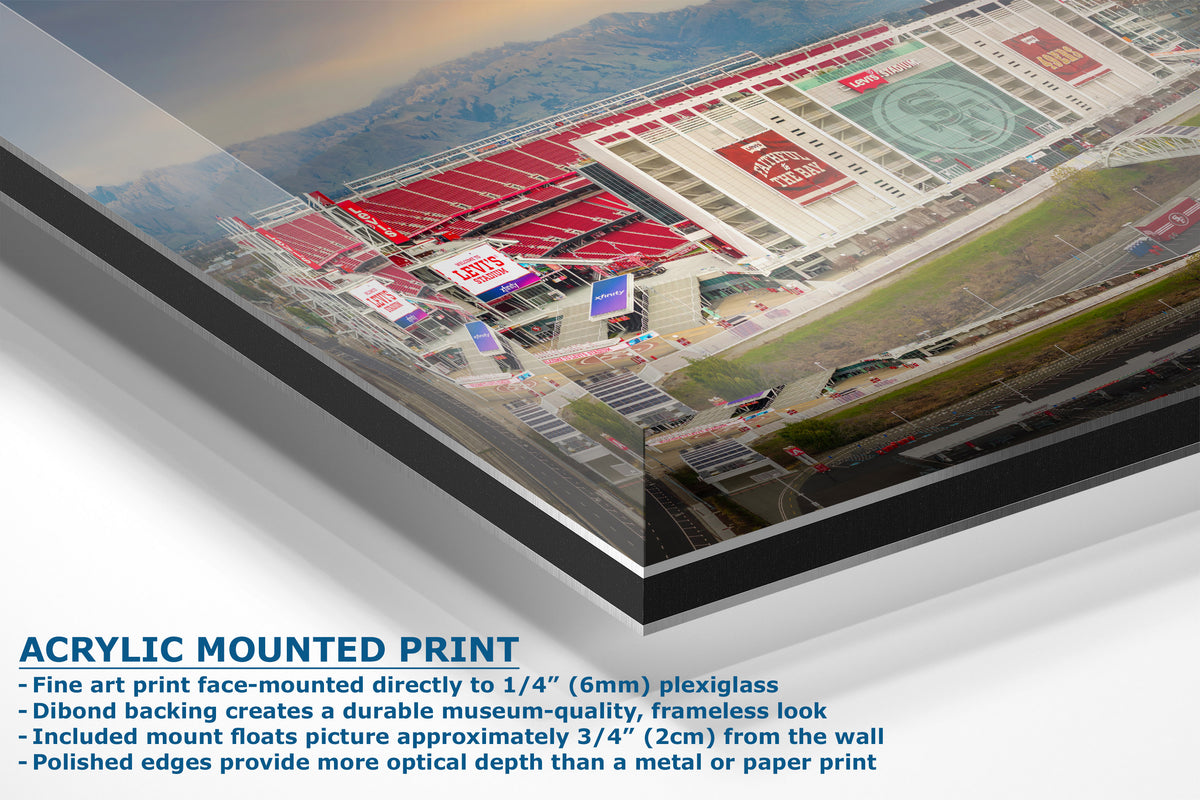 A corner view of an acrylic mounted art print of an aerial stadium scene, shown at an angle with descriptive text on a white background.
