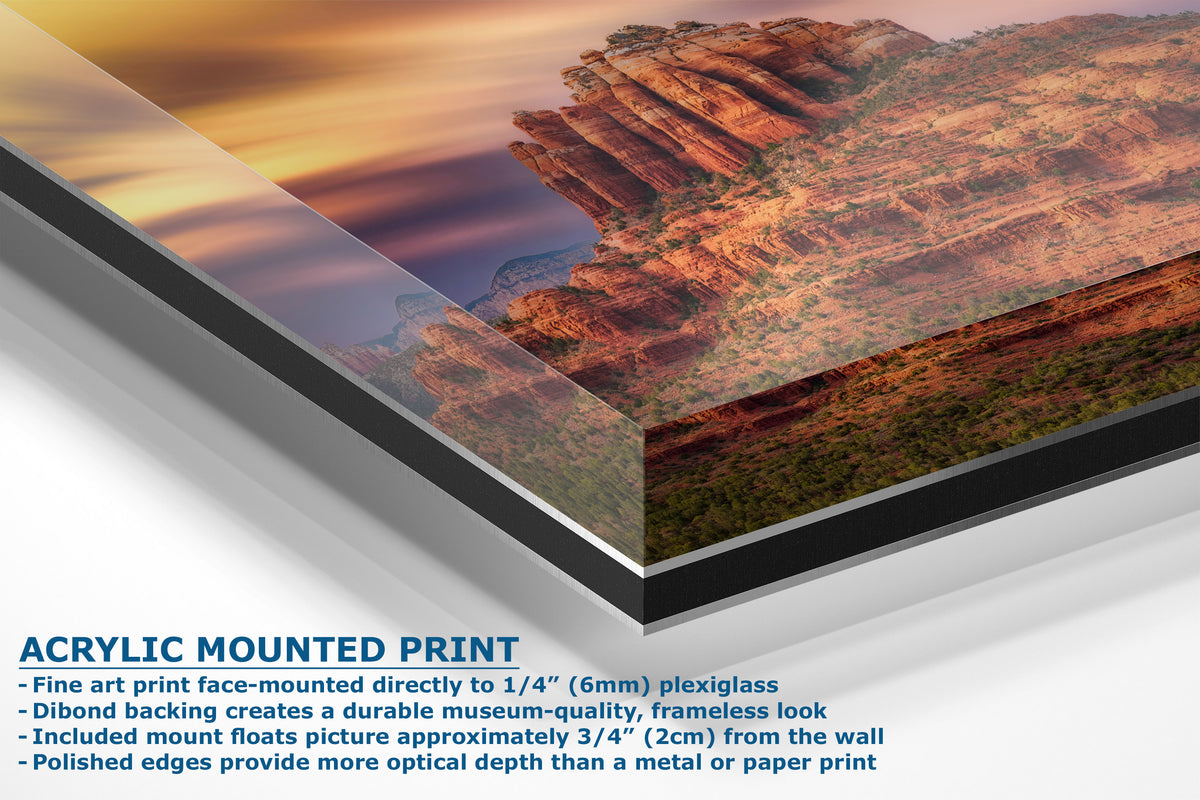 A corner view of an acrylic-mounted art print of a desert canyon landscape at sunset, shown at an angle with descriptive text on a white background.