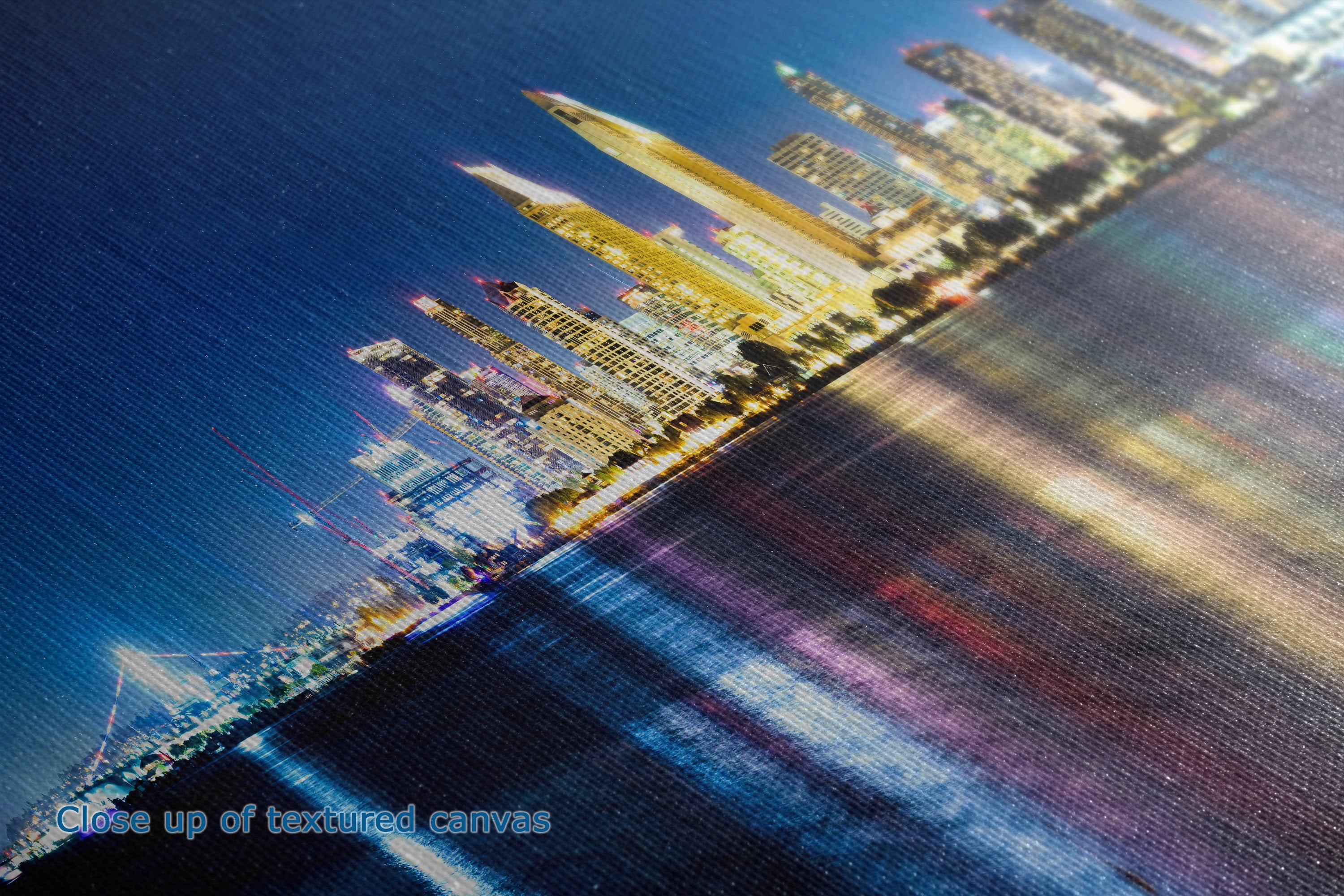 Close-up of a textured canvas print depicting a vibrant city skyline at night with illuminated skyscrapers and colorful reflections on water.
