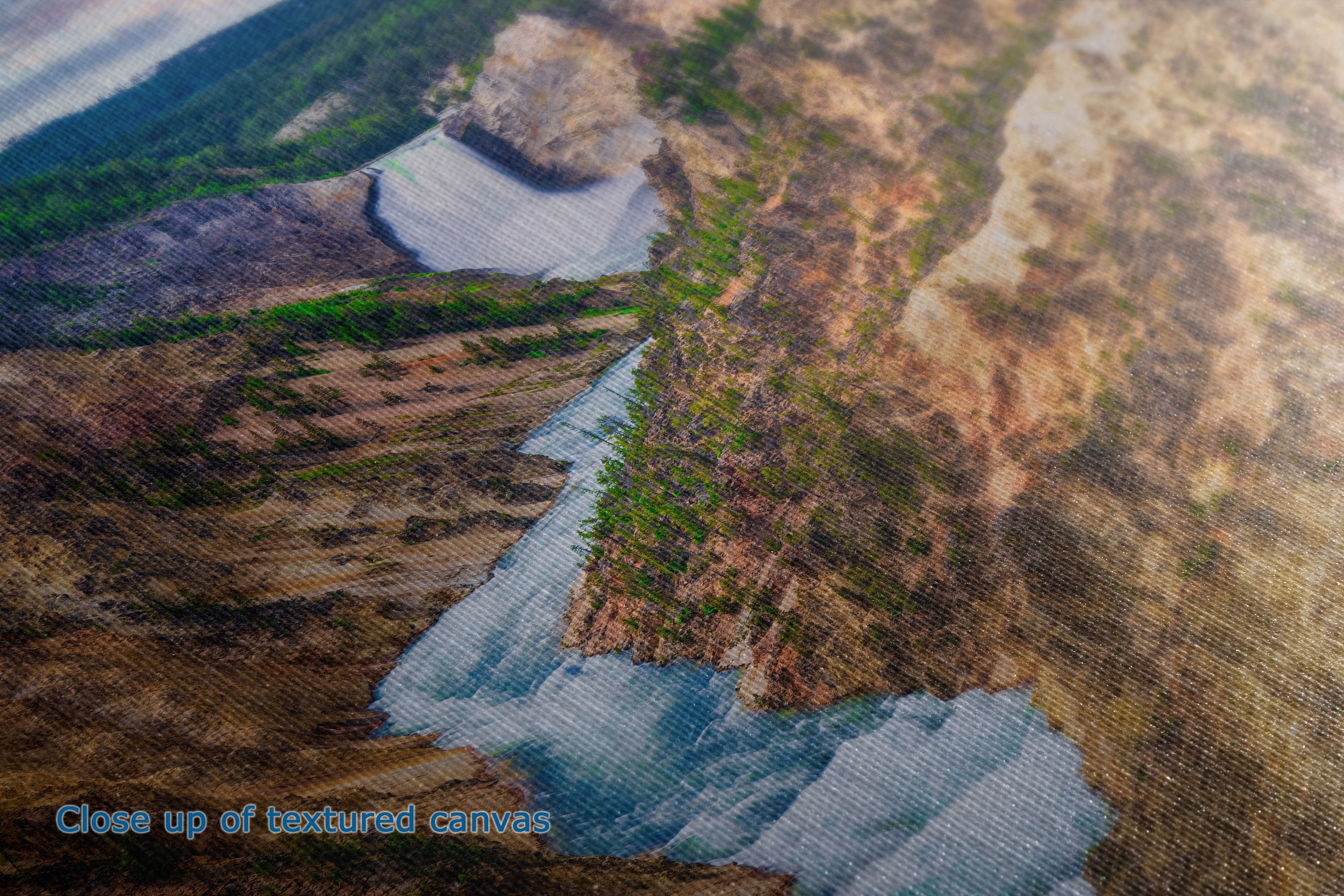 A close-up of a textured canvas print depicting a mountain landscape with a waterfall, showing brown rocky cliffs, green vegetation, and blue-gray water. Text in the bottom-left corner reads 'Close up of textured canvas'.