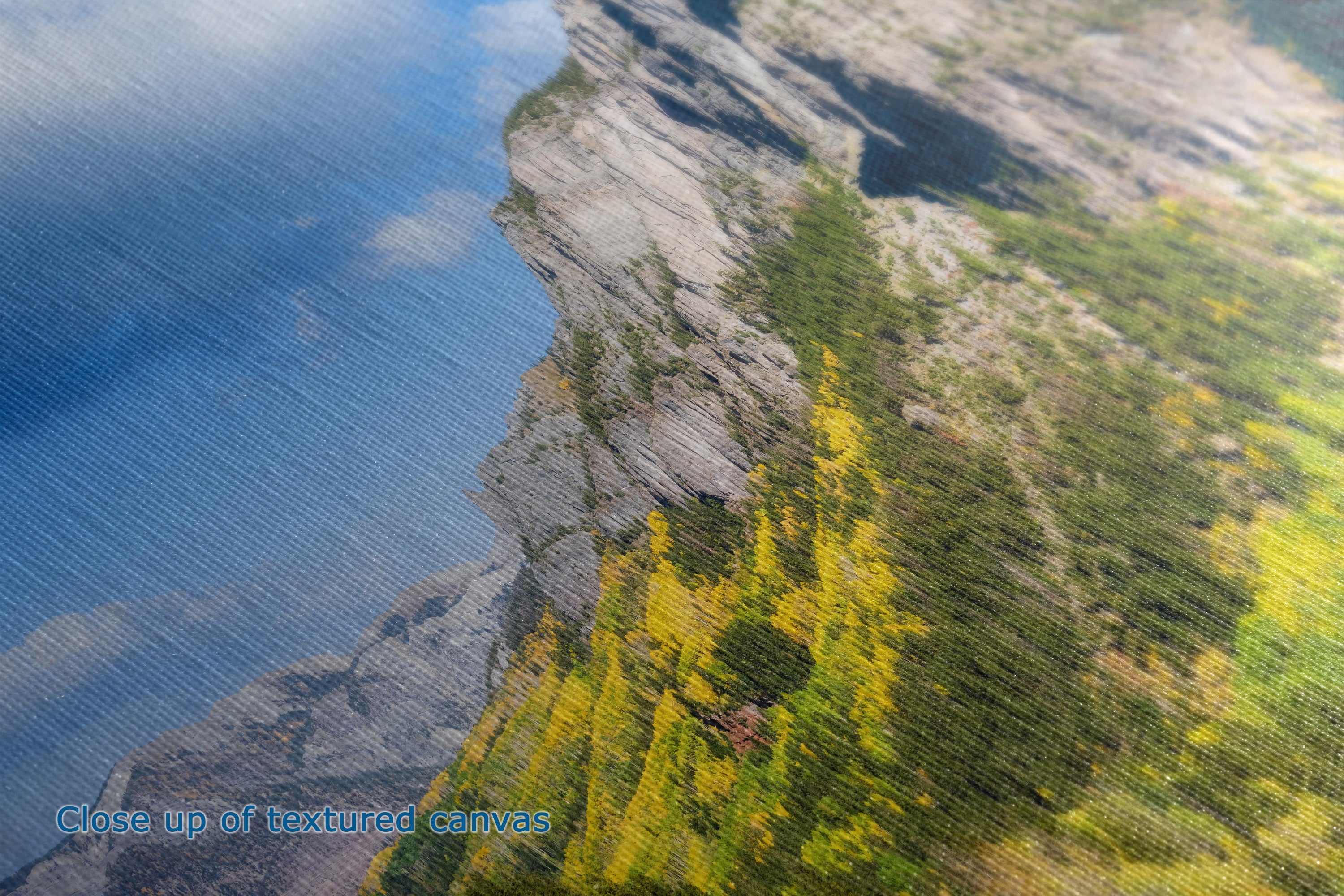 Close-up detailed view of the texture of a canvas print depicting a dramatic mountainscape with steep rocky cliffs and green and yellow autumn trees.