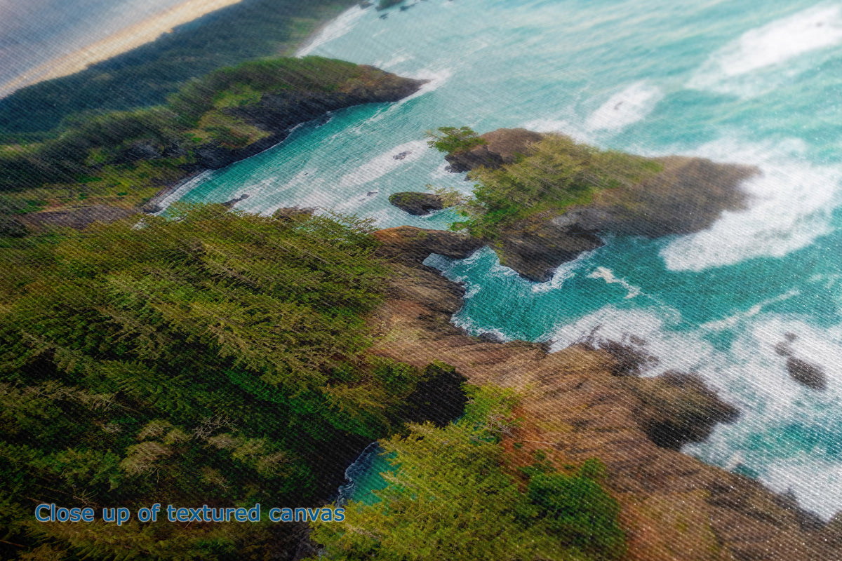 A close-up of a textured canvas print depicting an aerial coastal landscape with green cliffs, rocky shores, and turquoise ocean waves crashing. Blue text in the lower-left corner reads 'Close up of textured canvas'.
