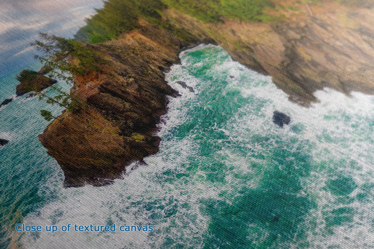 Close-up of a textured canvas print depicting a coastal landscape with turquoise ocean waves crashing against rocky cliffs topped with green vegetation.