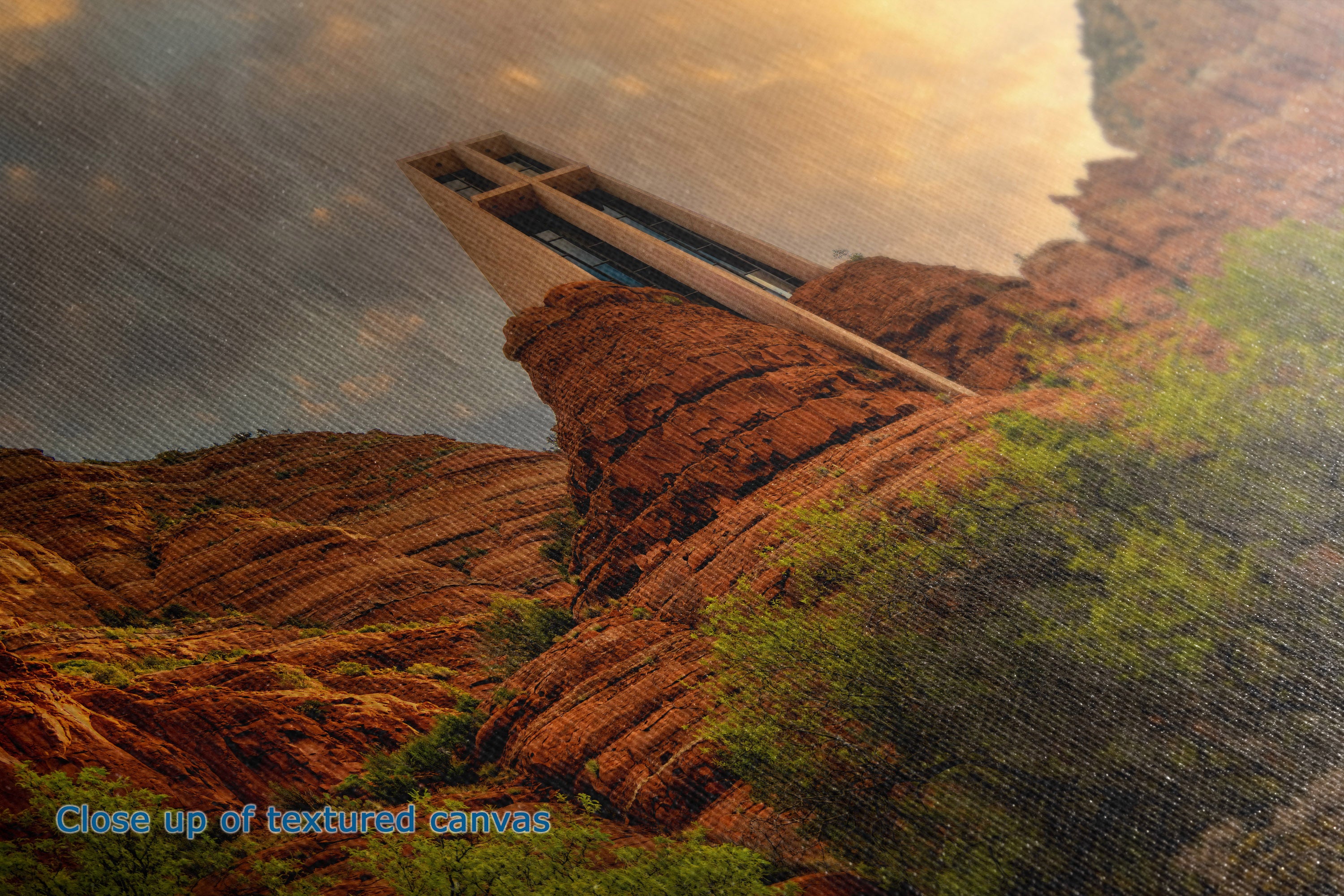 A close-up of the detail and texture of a canvas print depicting a canyon landscape with reddish-brown rock formations, green vegetation, and a warm golden sky. A small blue text overlay in the bottom-left corner reads 'Close up of textured canvas'.