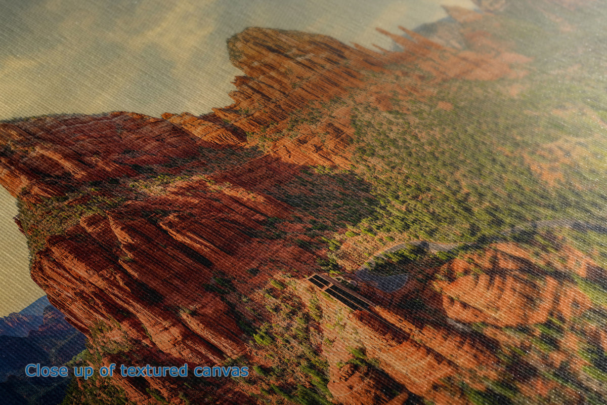 Close-up of a textured canvas print depicting a desert canyon landscape with red rock cliffs and green vegetation under a cloudy sky.