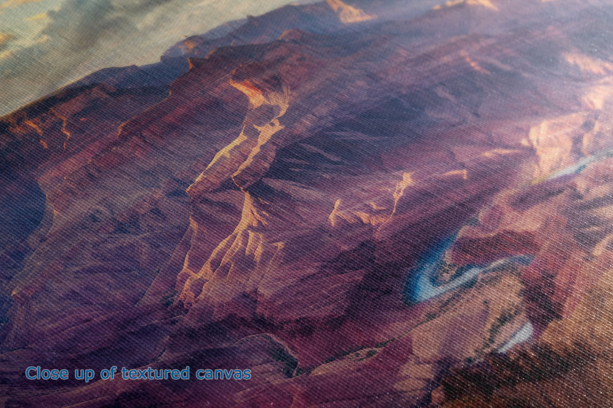 Close-up of a textured canvas print depicting a canyon landscape with warm orange and purple-brown tones, showing the fabric weave detail.