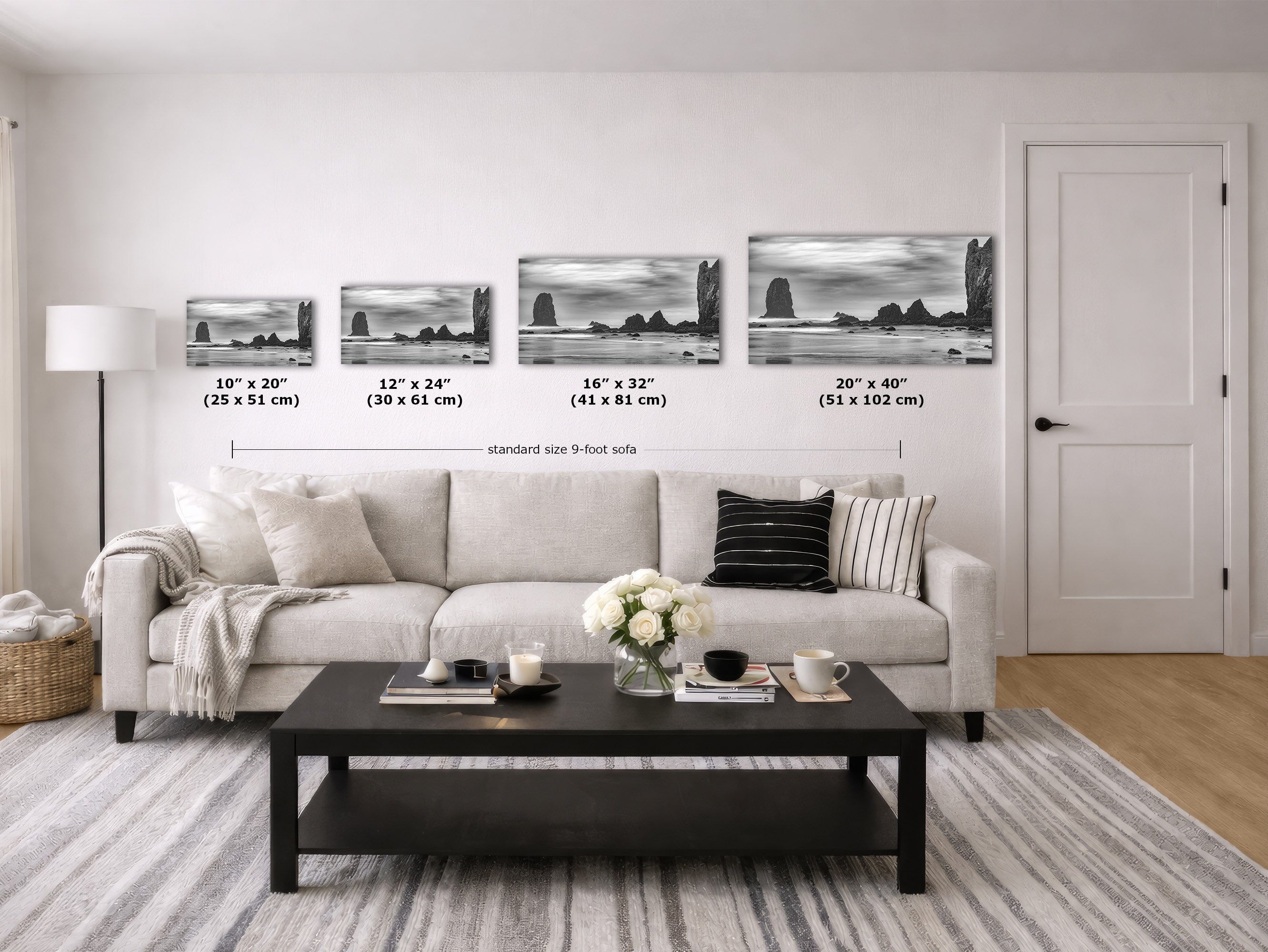 A staged living room showing four framed black-and-white coastal landscape prints mounted on a white wall above a sofa. 