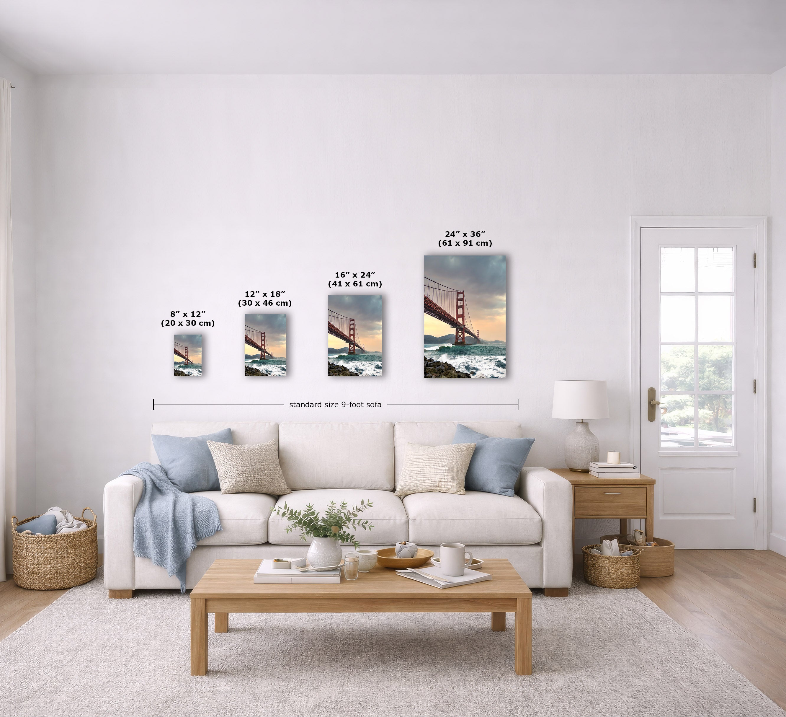 A staged living room shows a set of four vertical canvas prints of the Golden Gate Bridge with size labels overlaid above each canvas and a dimension line across the set. The room includes a white sofa, wooden coffee table, side table, lamp, baskets, and a white door.