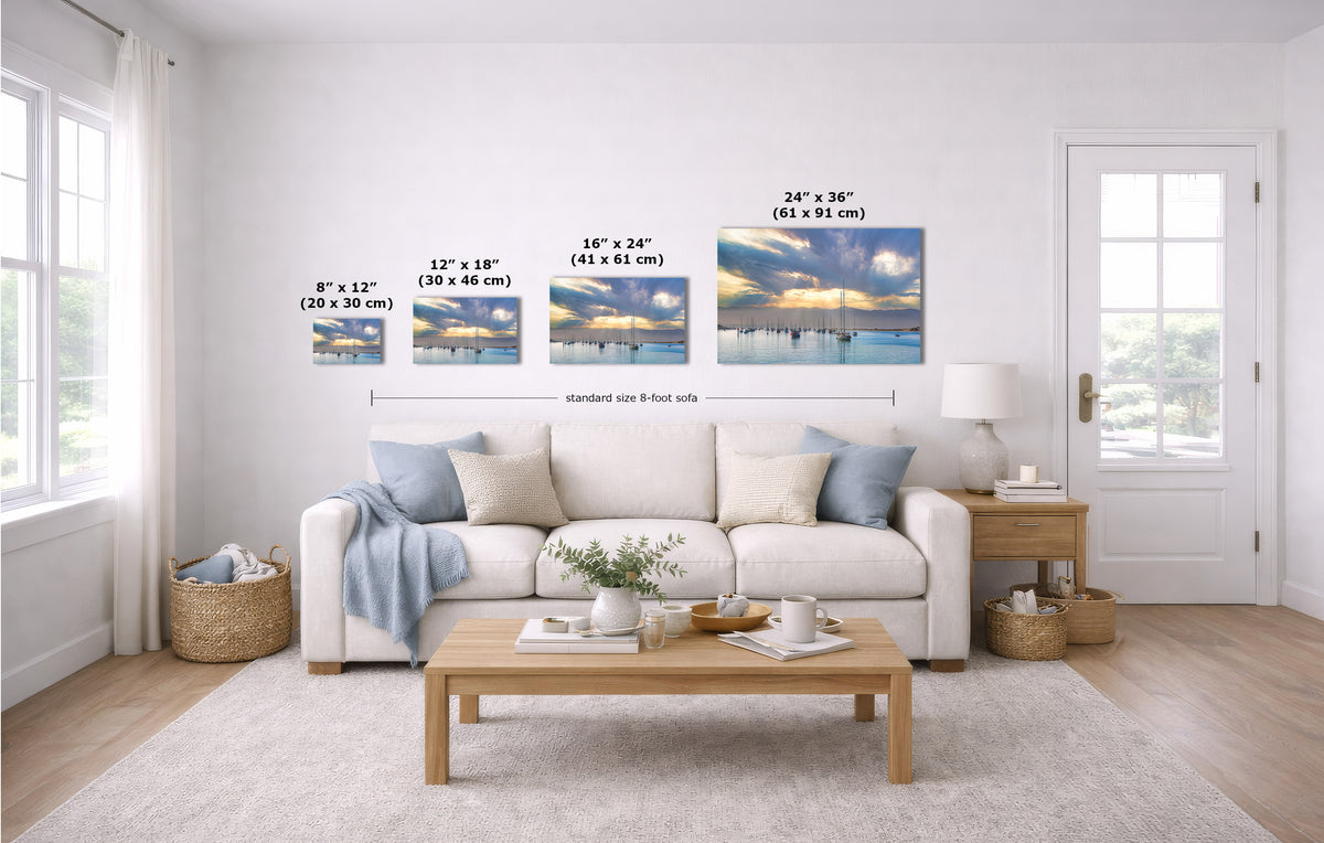A staged living room with a white sofa, coffee table, and wall-mounted art. The product being shown is the set of four landscape wall prints, with overlaid size labels ranging from 8 x 12 to 24 x 36 inches.