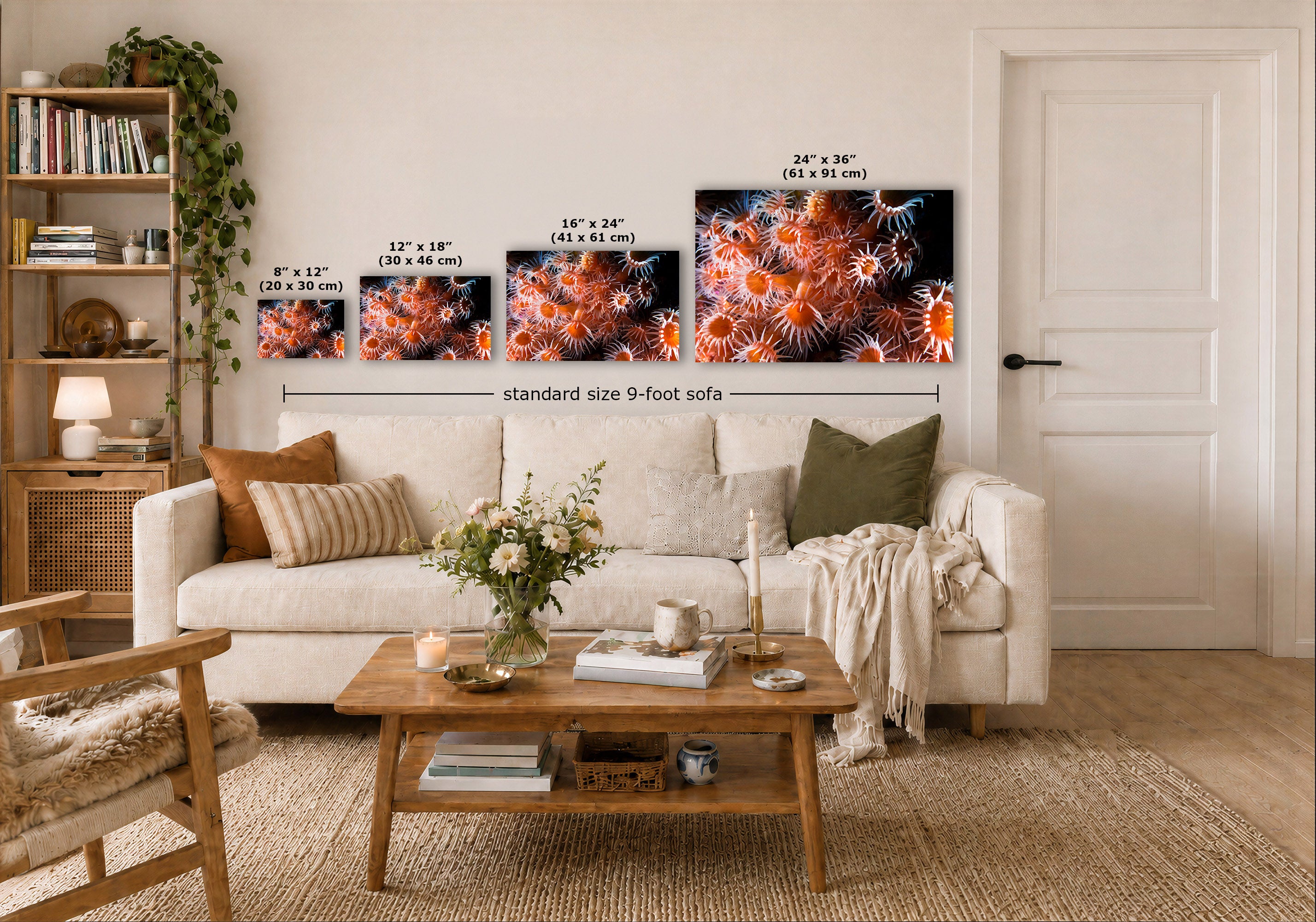 A styled living room showing four wall art prints above a white sofa, with size labels overlaid for each print. The prints depict vivid orange and red coral or anemone abstract marine imagery.