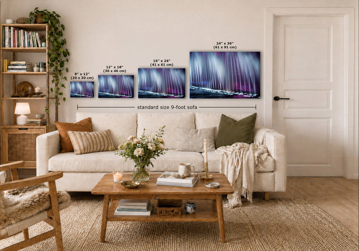 A staged living room showing a set of four wall art prints above a sofa, with size callouts for each print and a note for a 9-foot sofa. The prints depict a purple and blue abstract scene over water.