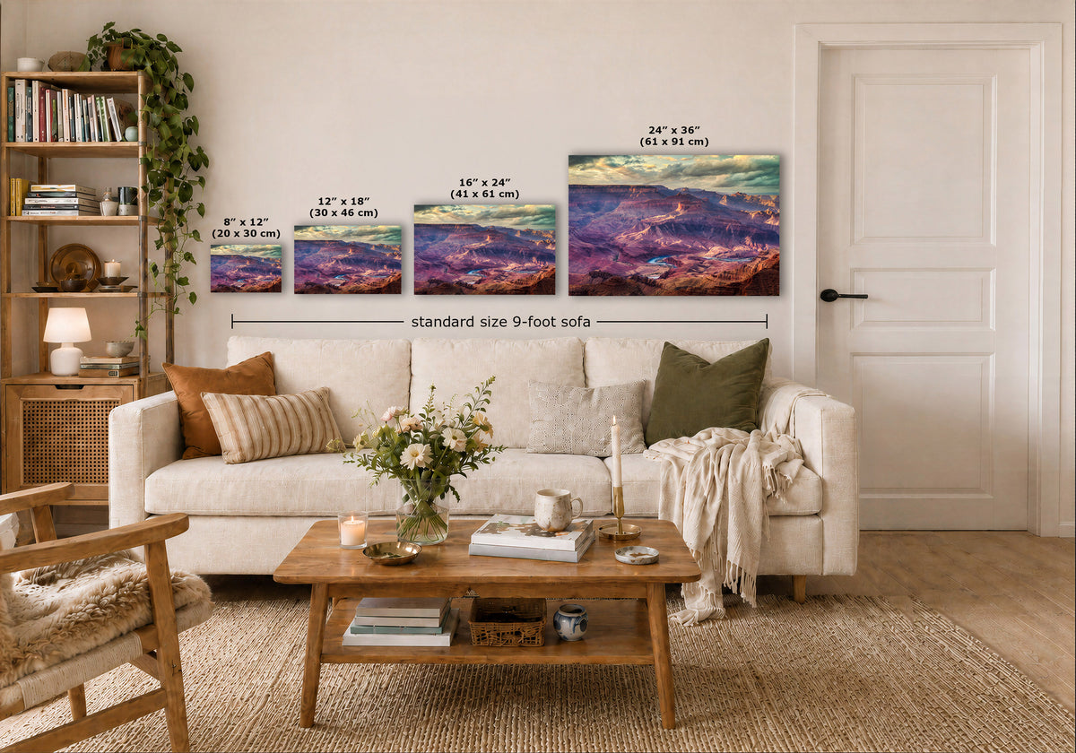 A staged living room showing four wall art prints above a white sofa, with size labels overlaid for each print. The artwork depicts colorful mountain or canyon landscapes in purple, blue, pink, and orange tones.