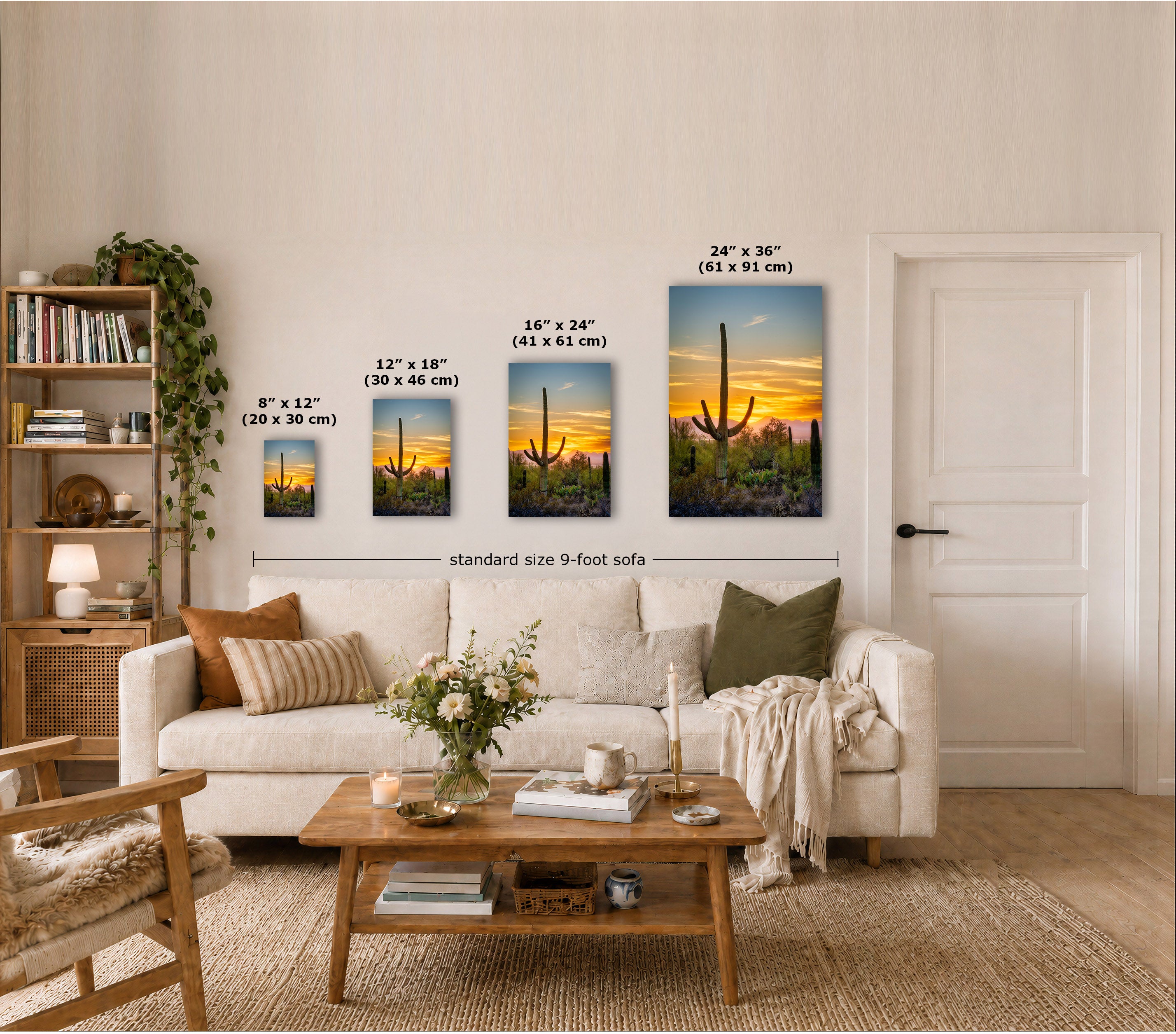 A staged living room shows a set of four vertical wall art prints with cactus desert sunset scenes, labeled by sizes in inches and centimeters. The prints are displayed above a cream sofa, with a coffee table, books, and a plant in the room.