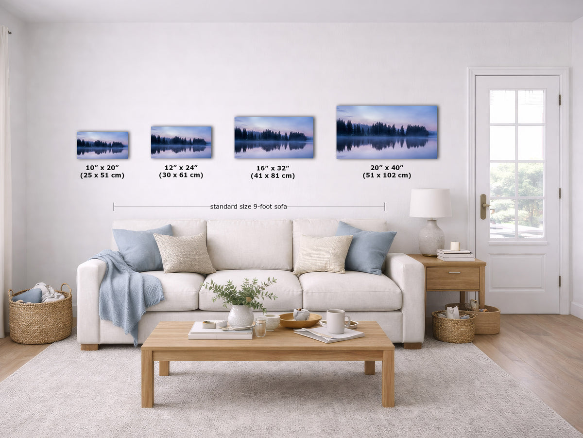A staged living room shows a set of four framed wall art prints above a sofa, each with size labels underneath. The prints depict a blue-toned forest lake scene.