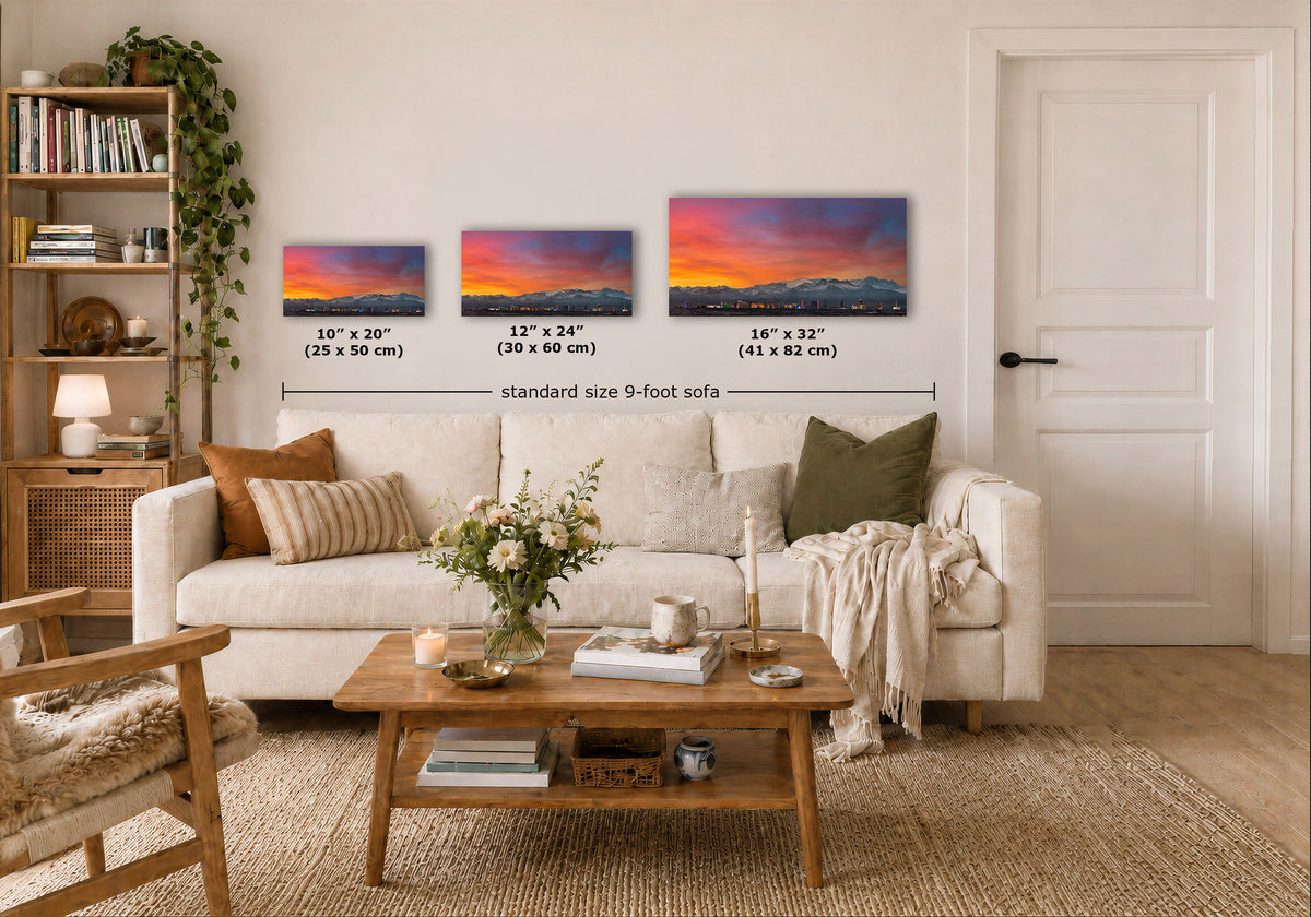 Three framed wall art prints showing colorful sunset landscapes are displayed above a white sofa in a styled living room. Text labels indicate the dimensions of each print.