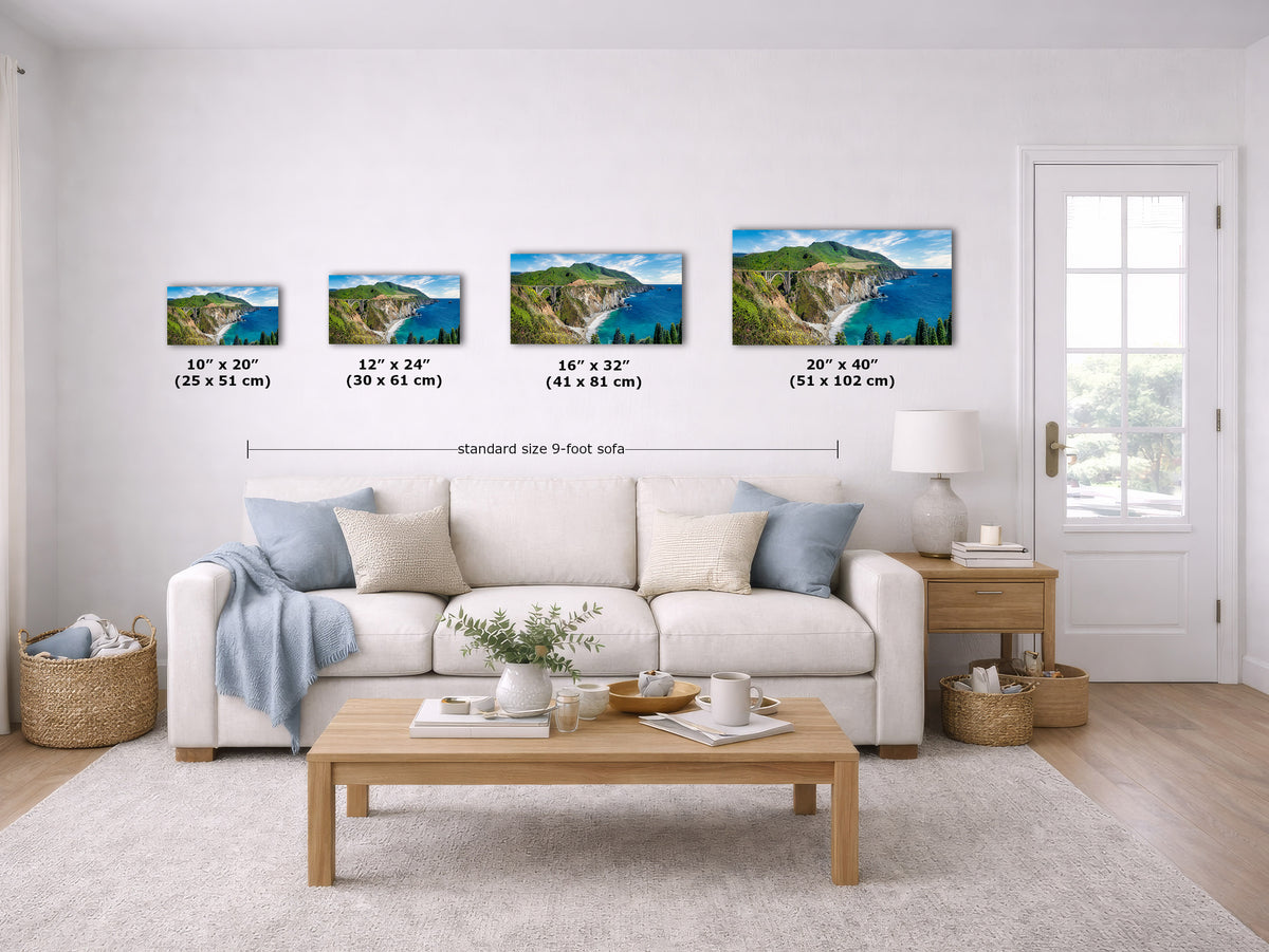 A staged living room shows a set of five landscape wall art prints above a white sofa, with size labels and a measurement line across the prints. The prints depict coastal cliffs and blue water scenes.