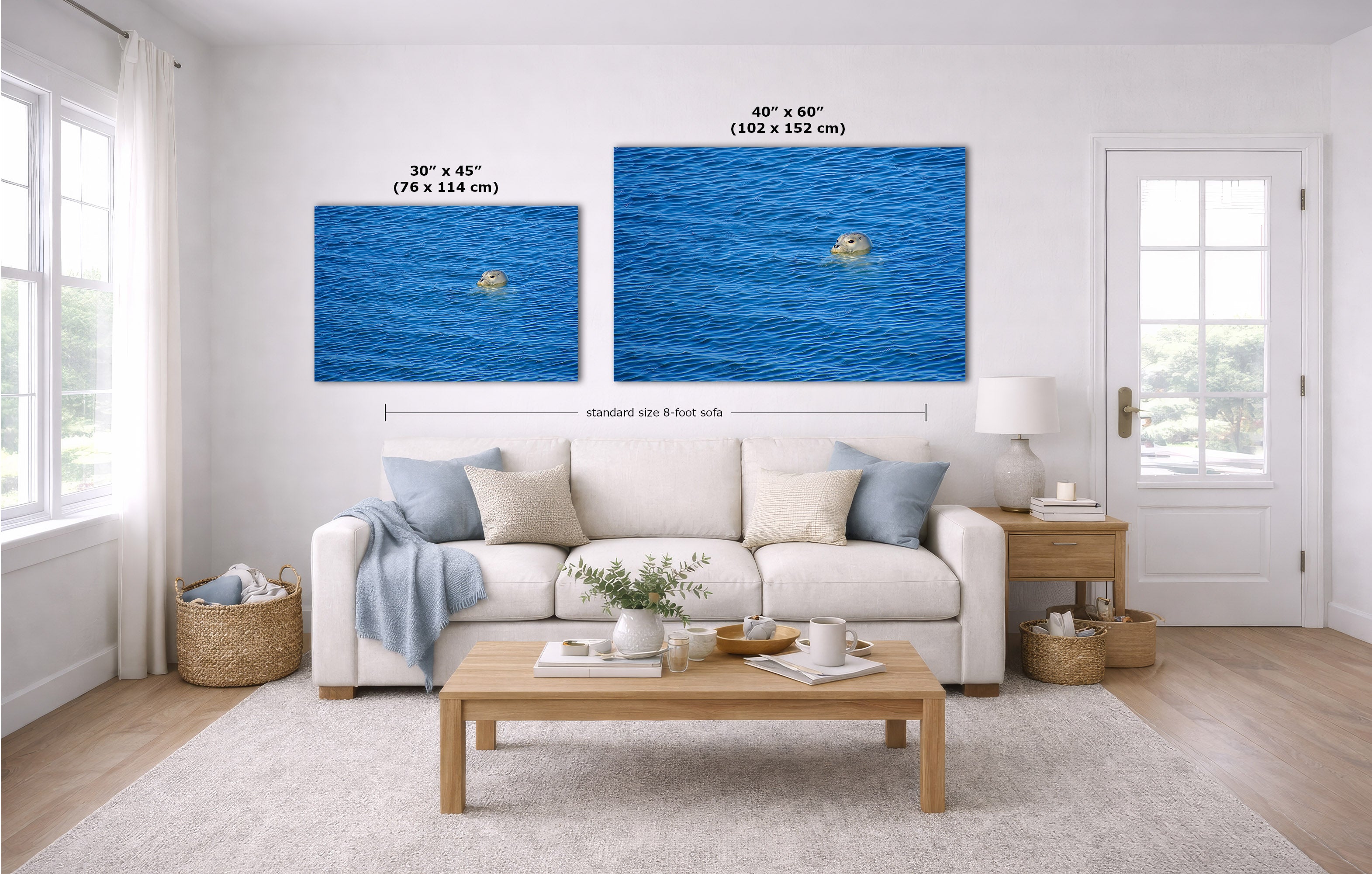 Two blue ocean canvas prints displayed on a white wall above a light beige sofa in a bright, modern living room. The left print is labeled 30 x 45 inches, and the larger right print is labeled 40 x 60 inches.